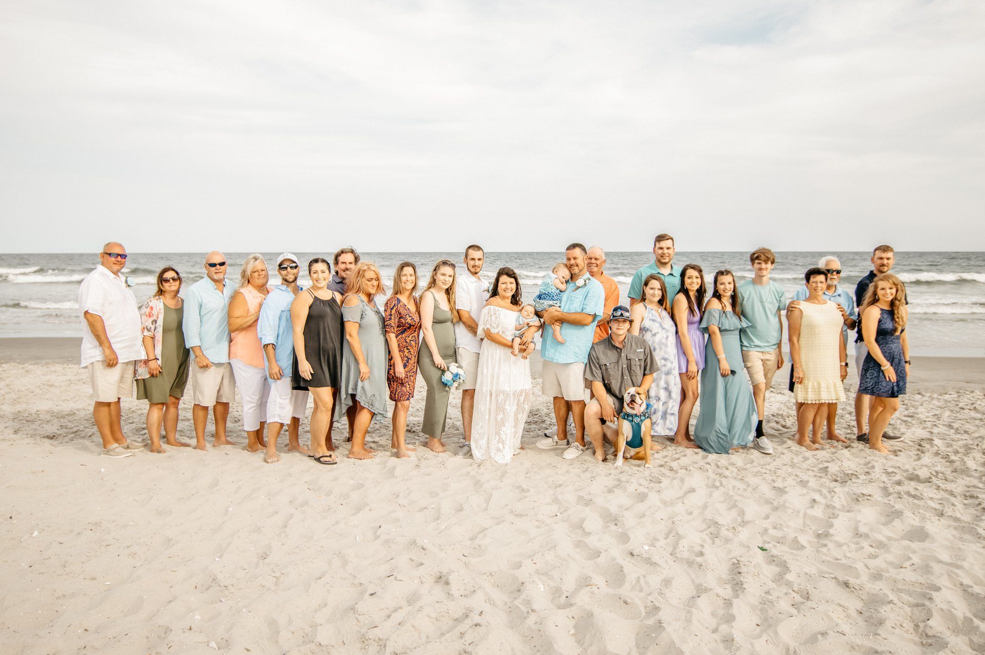 A large group of people are posing for a picture on the beach.