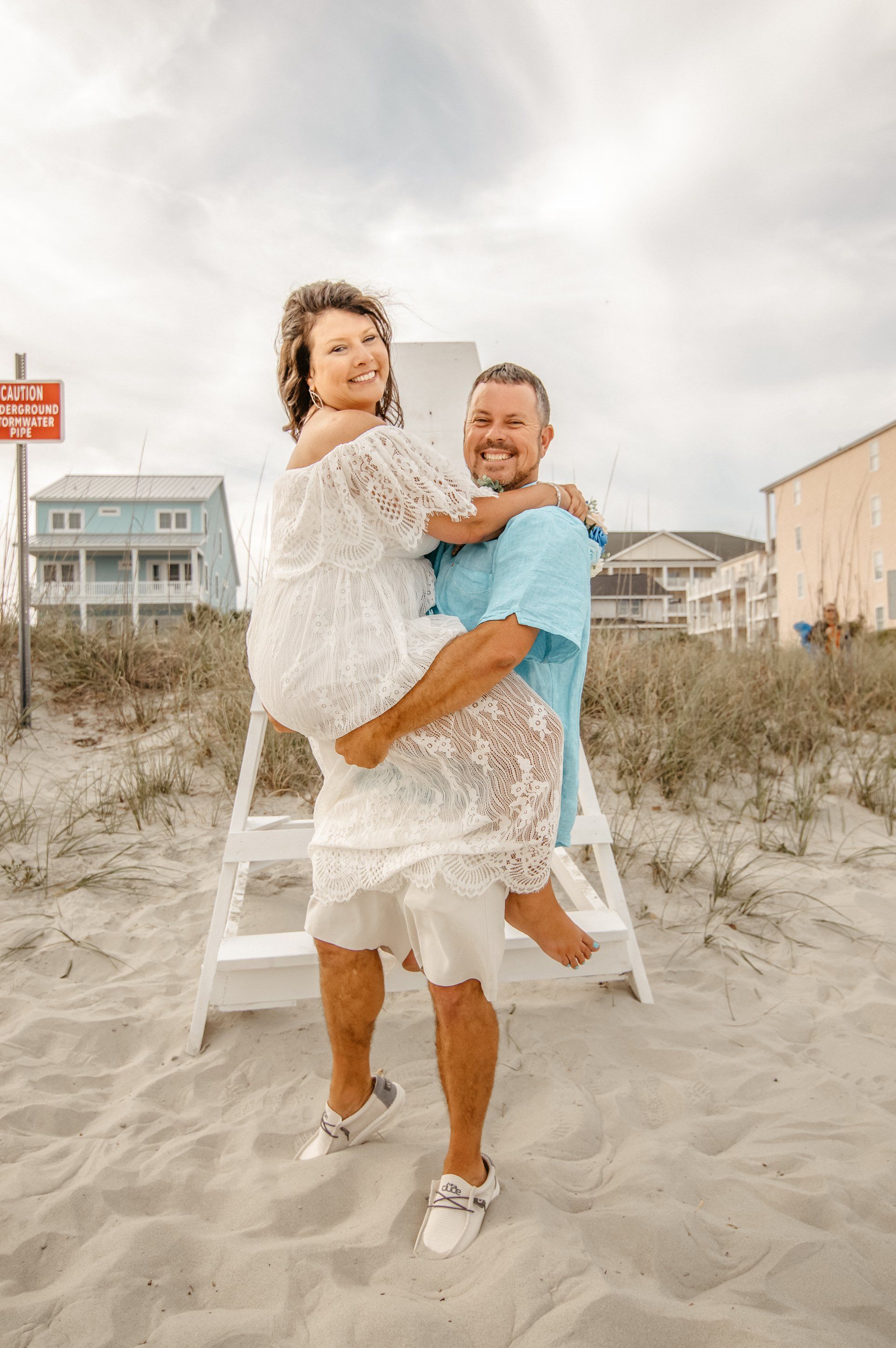 A man is holding a woman in his arms on the beach.