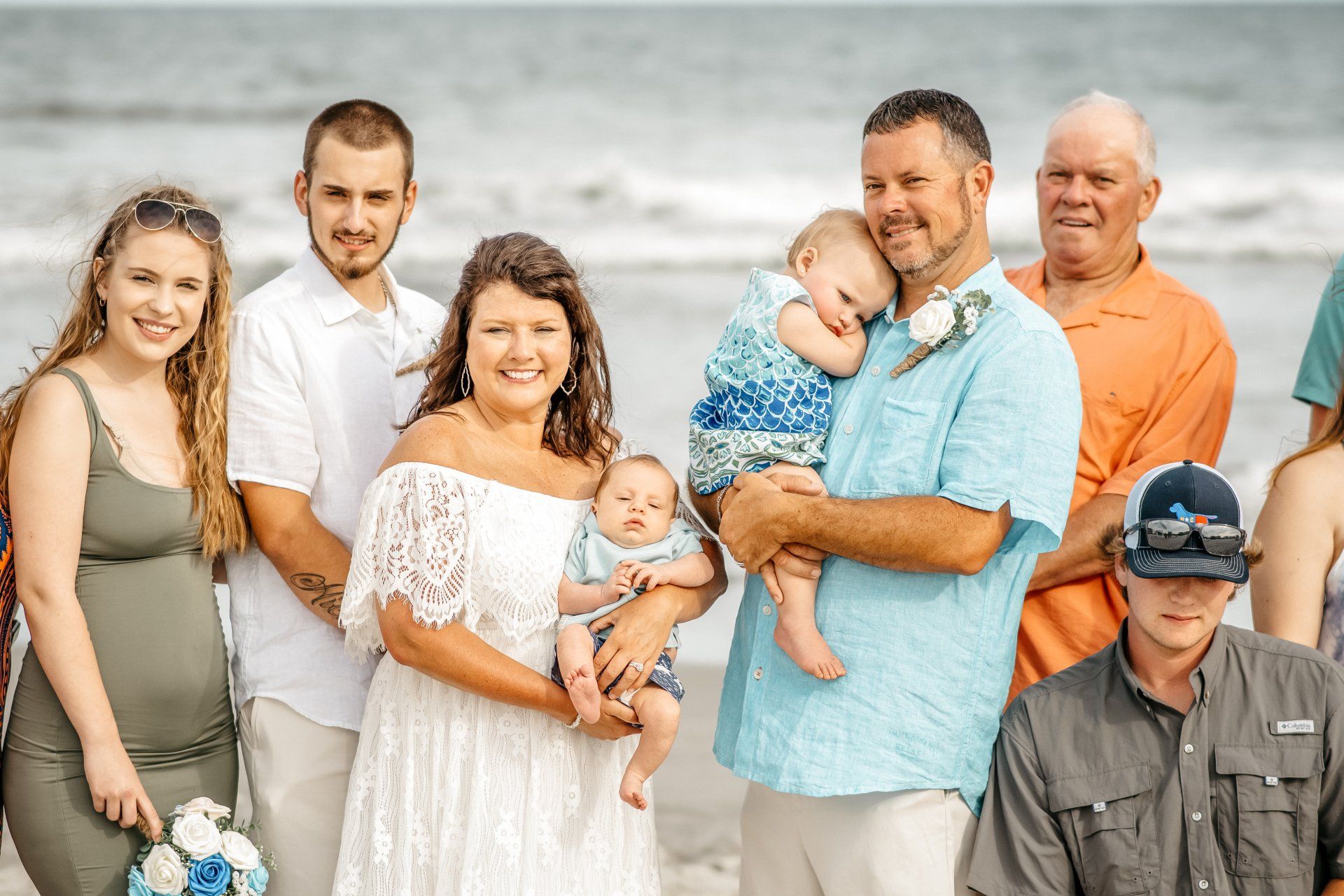 A group of people are posing for a picture on the beach.