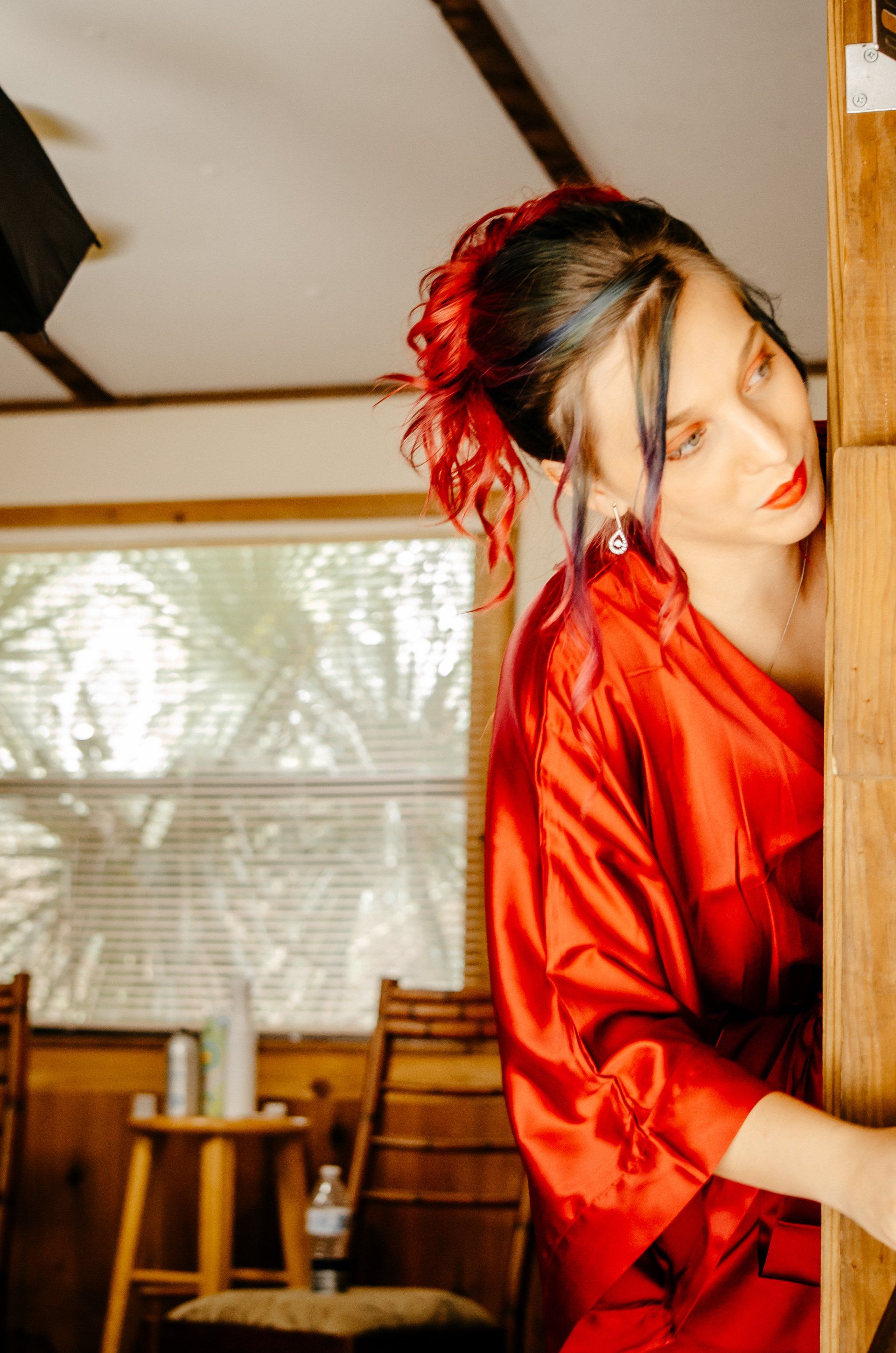 A woman in a red robe is leaning against a wall