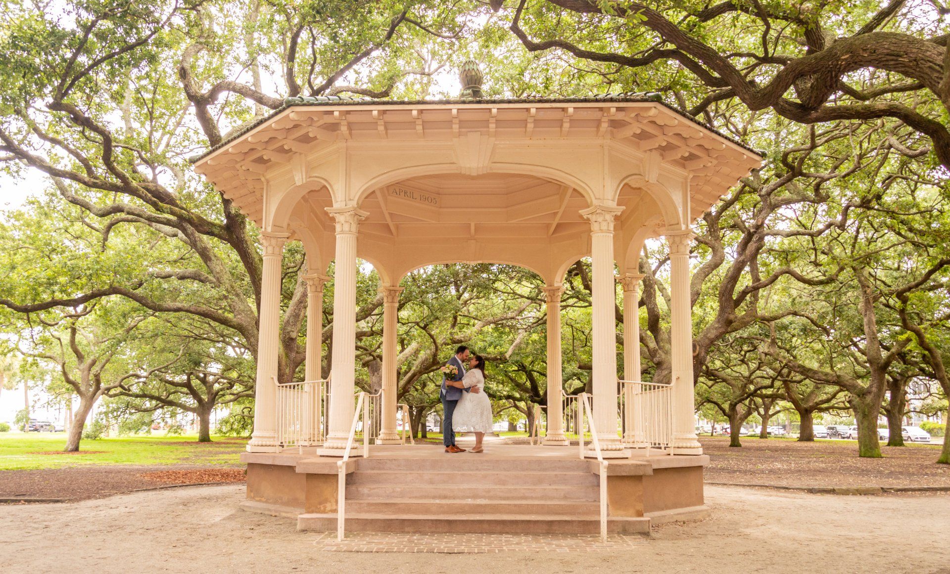 A man and woman are standing under a gazebo in a park.