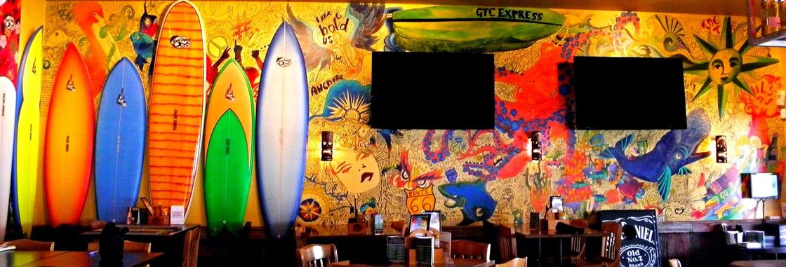 A restaurant with a mural of surfboards on the wall
