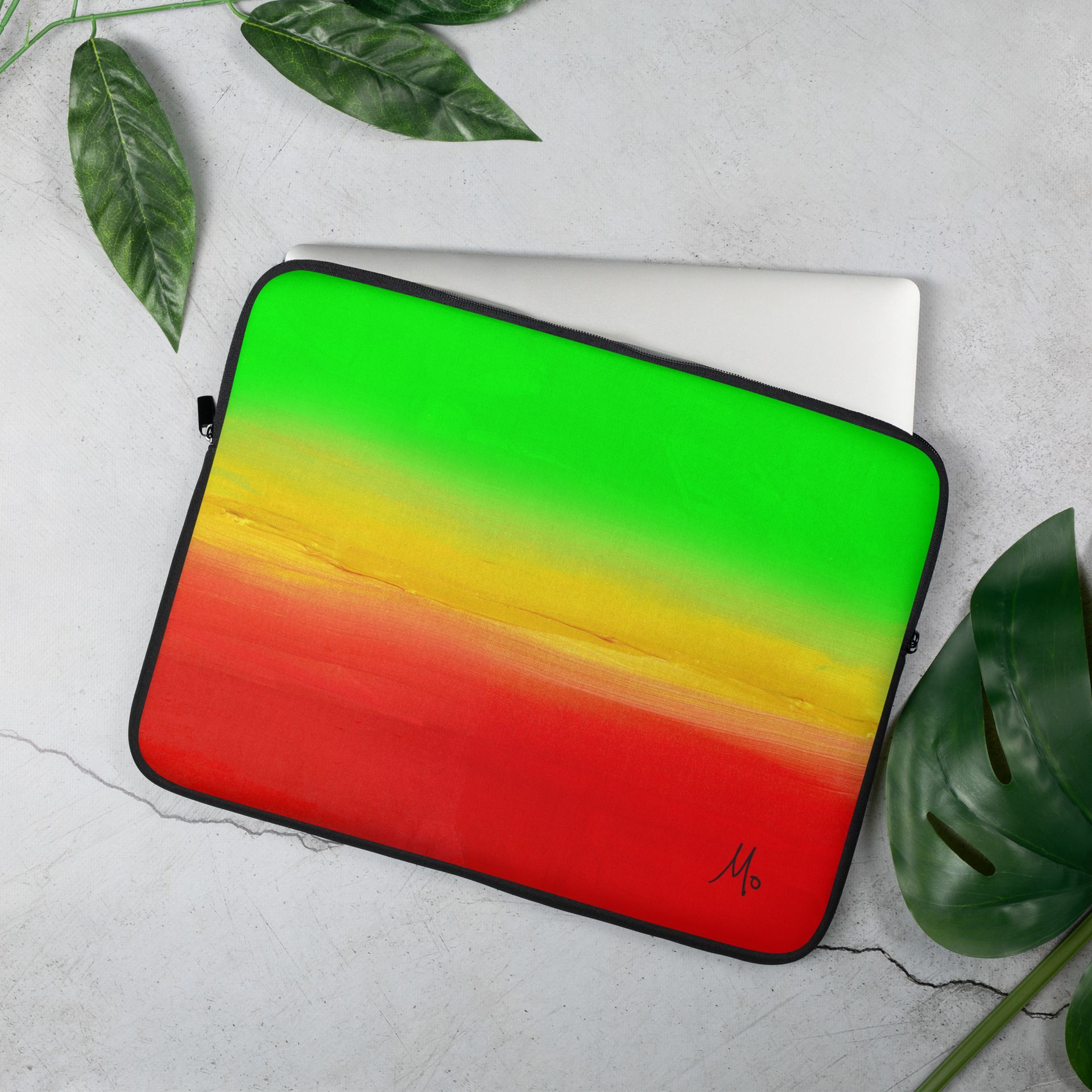 A laptop is sitting on a table next to a reggae flag sleeve