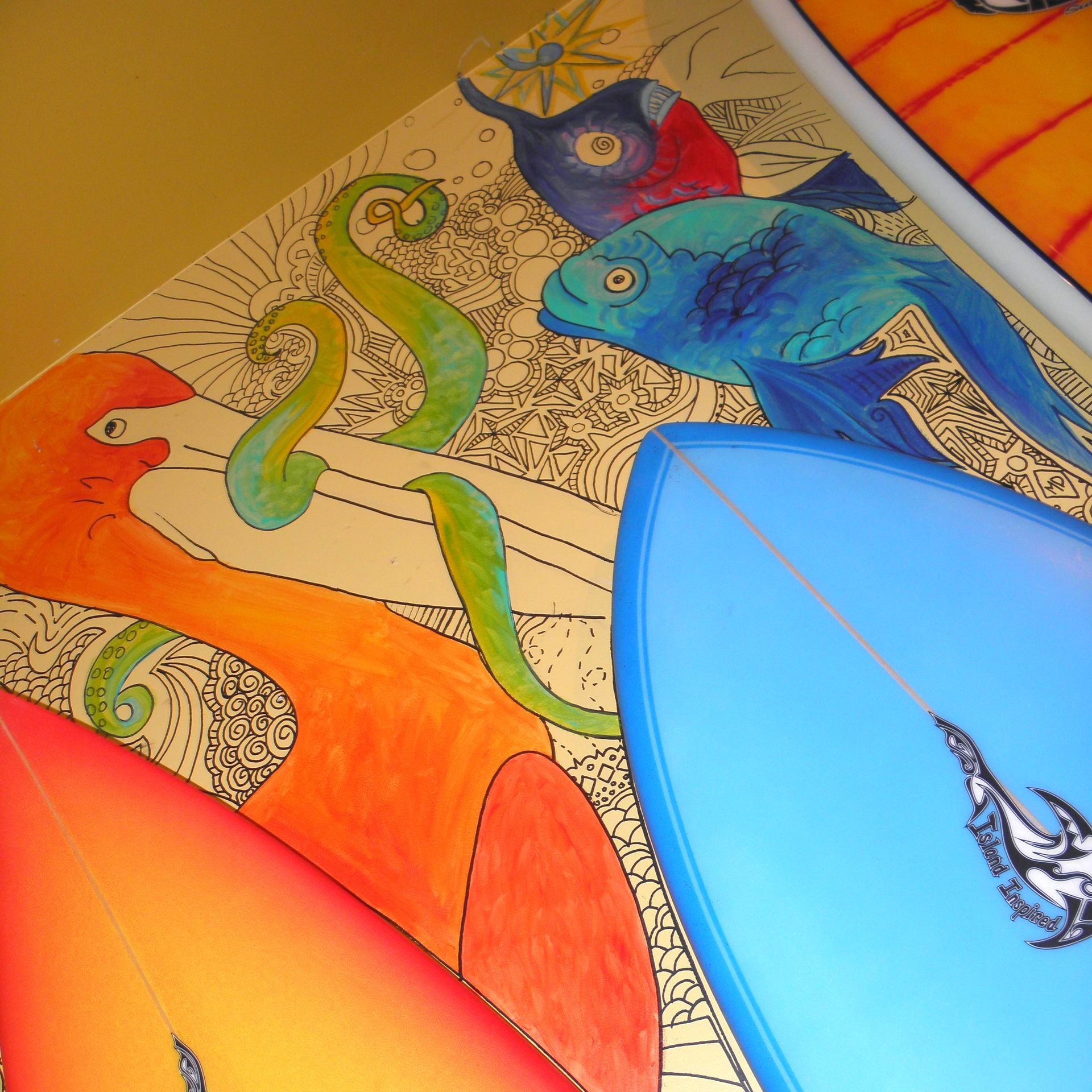 A blue surfboard is sitting on top of a colorful painting