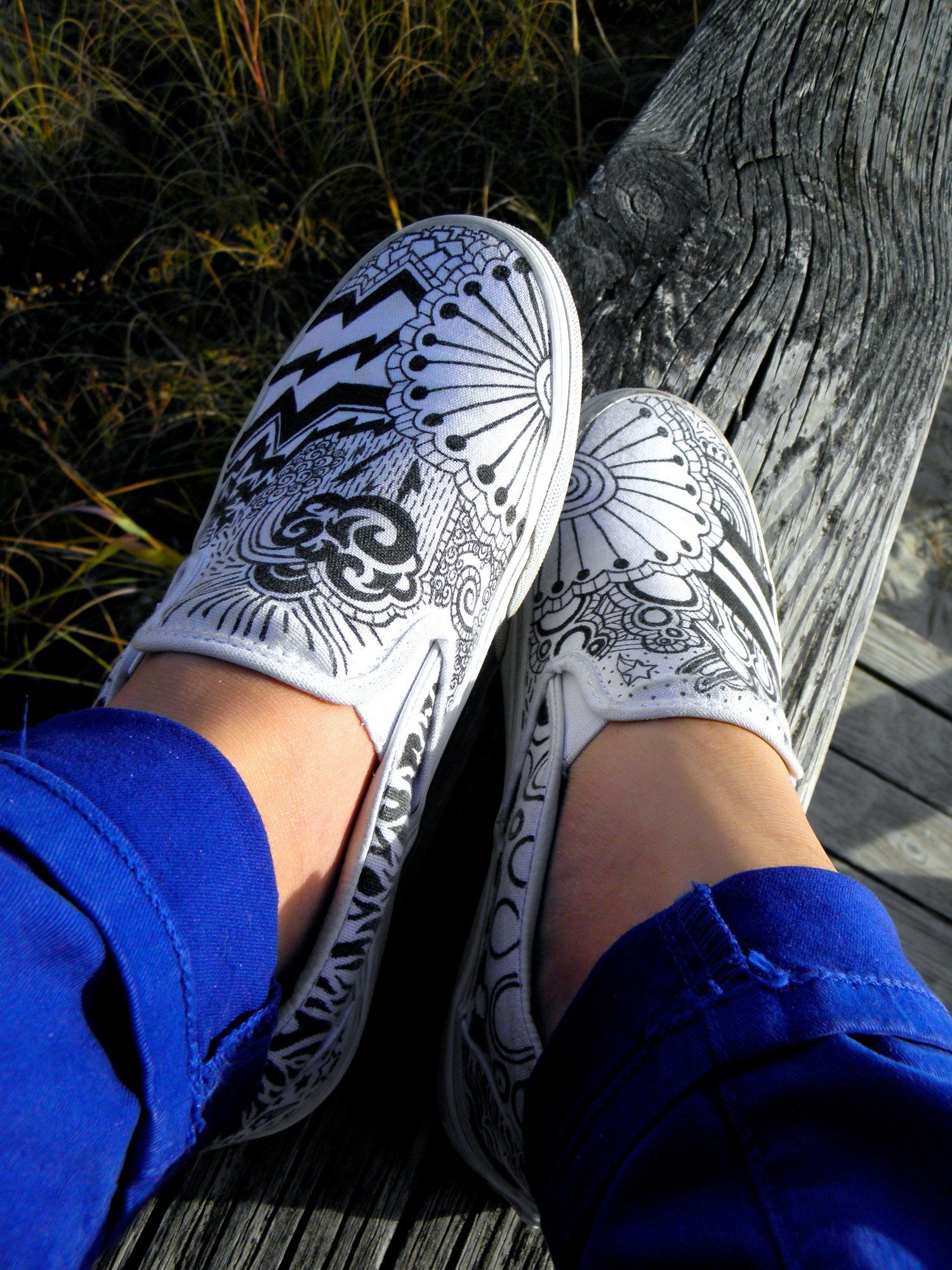 A person wearing a pair of white shoes with a design on them