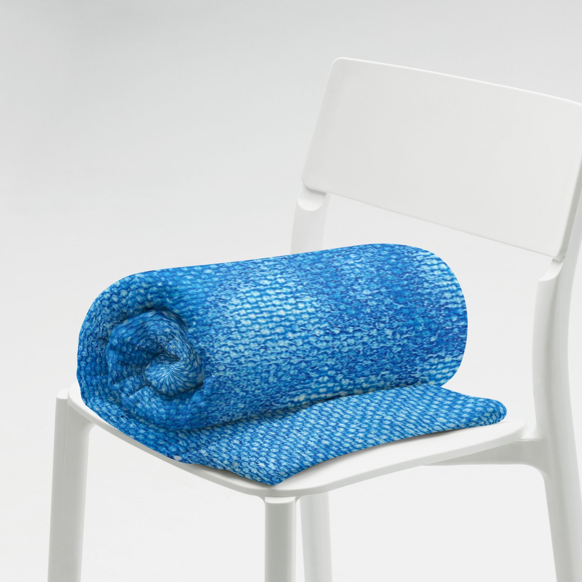 A blue blanket is rolled up on a white chair
