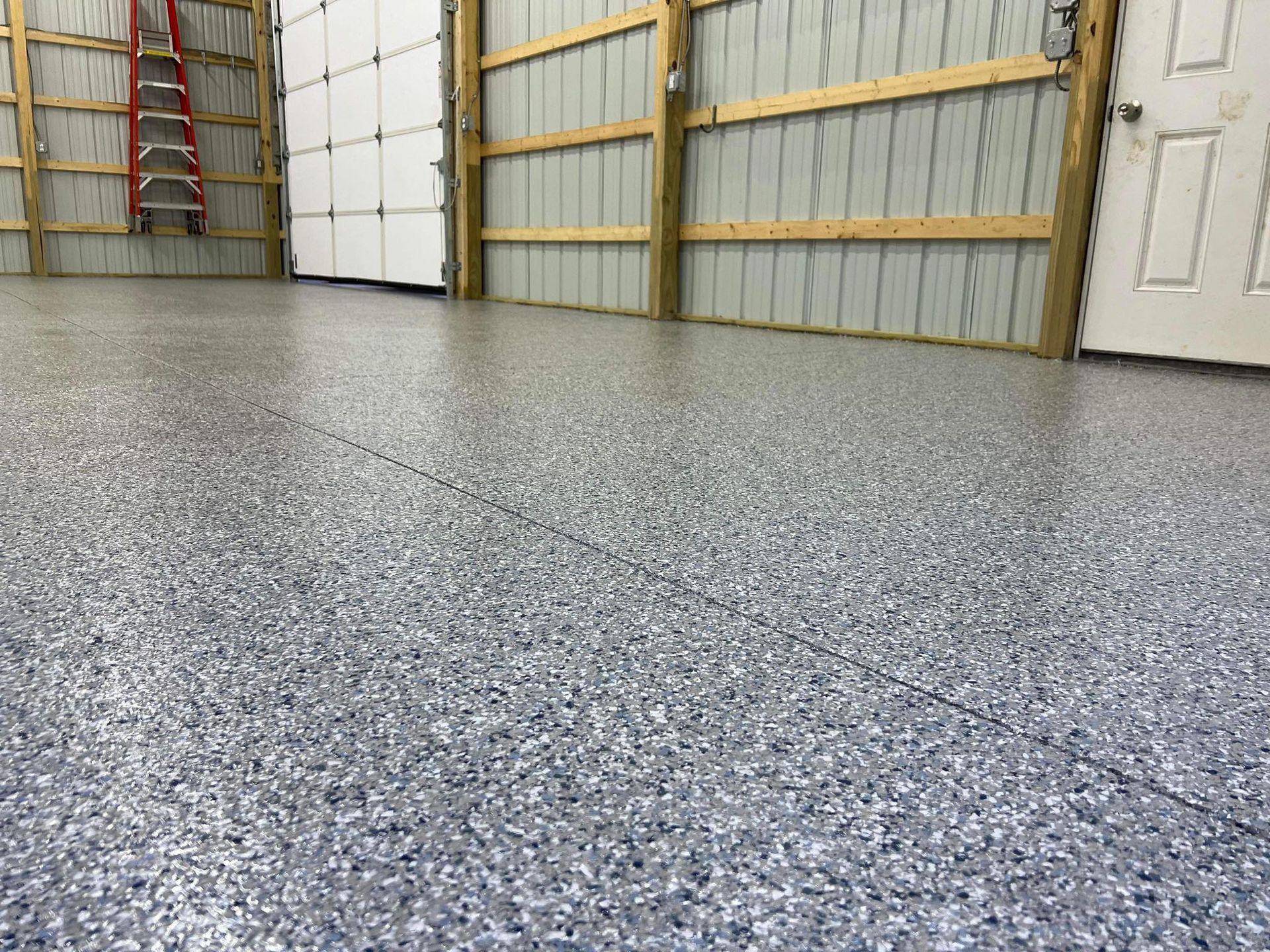 Epoxy garage floor with speckled gray and white finish, surrounded by light-colored walls and doors.