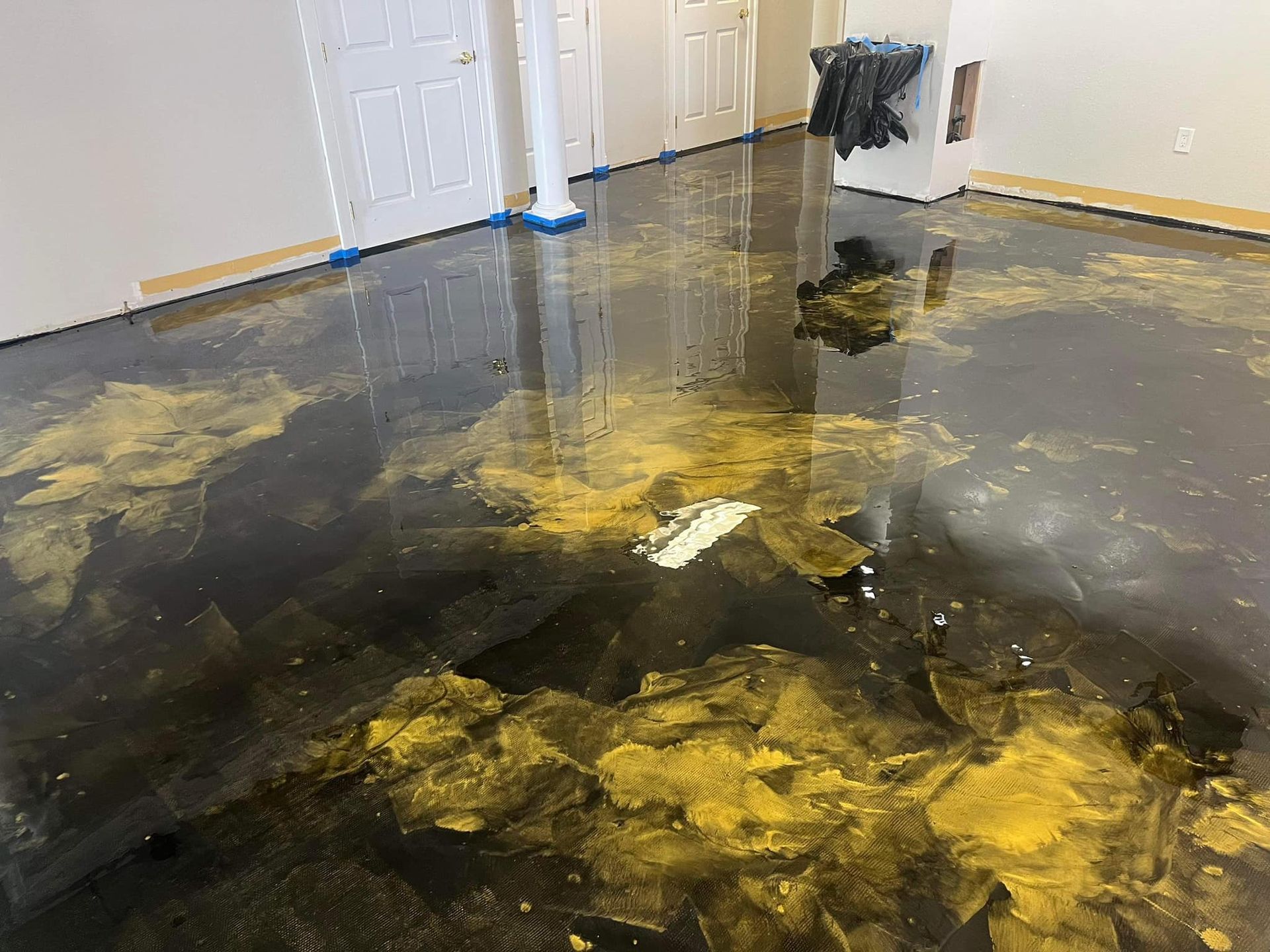 A black and gold epoxy floor in a room with white walls and doors.