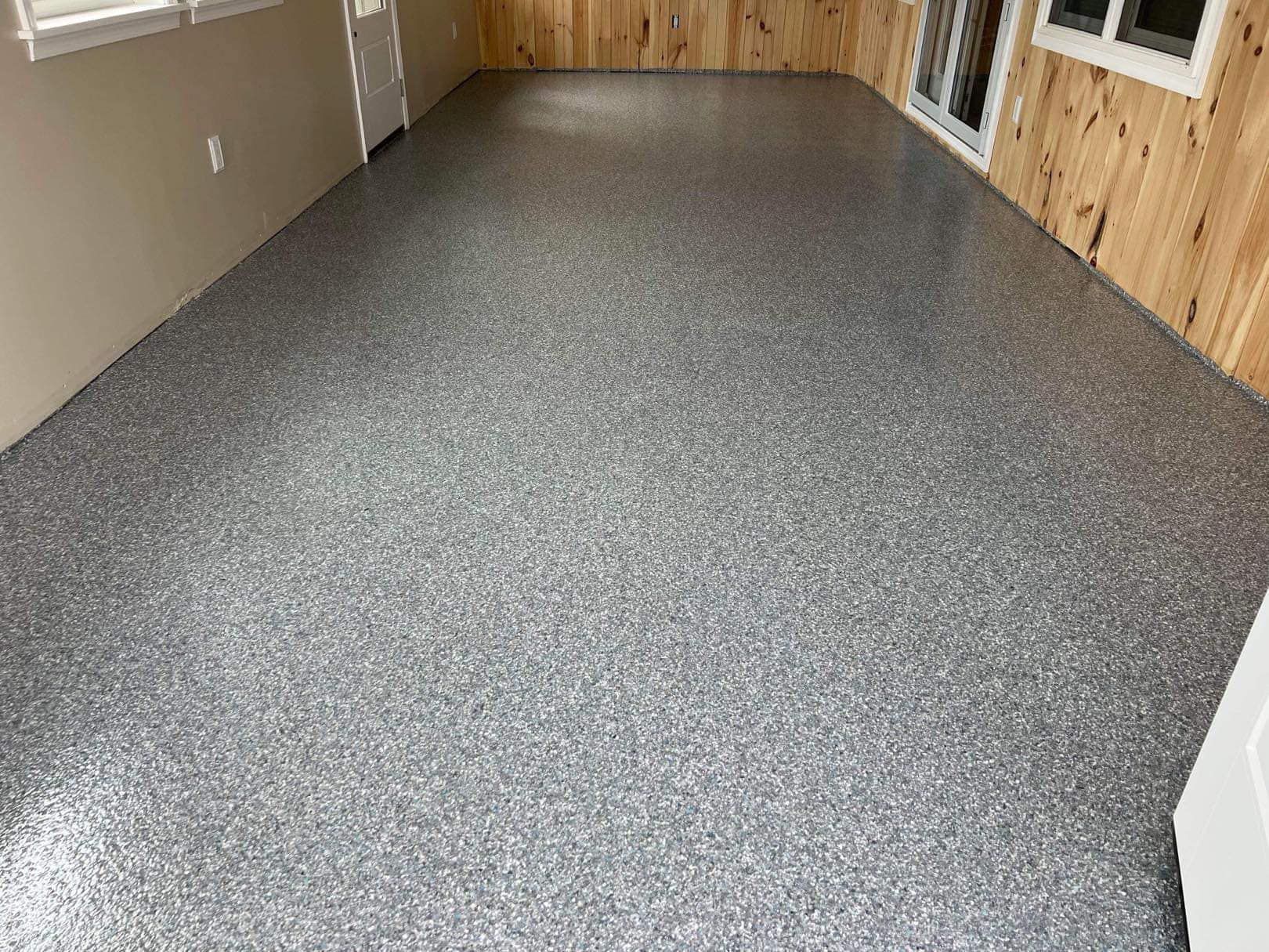 Gray speckled epoxy floor in a room with light wood paneling and beige walls.