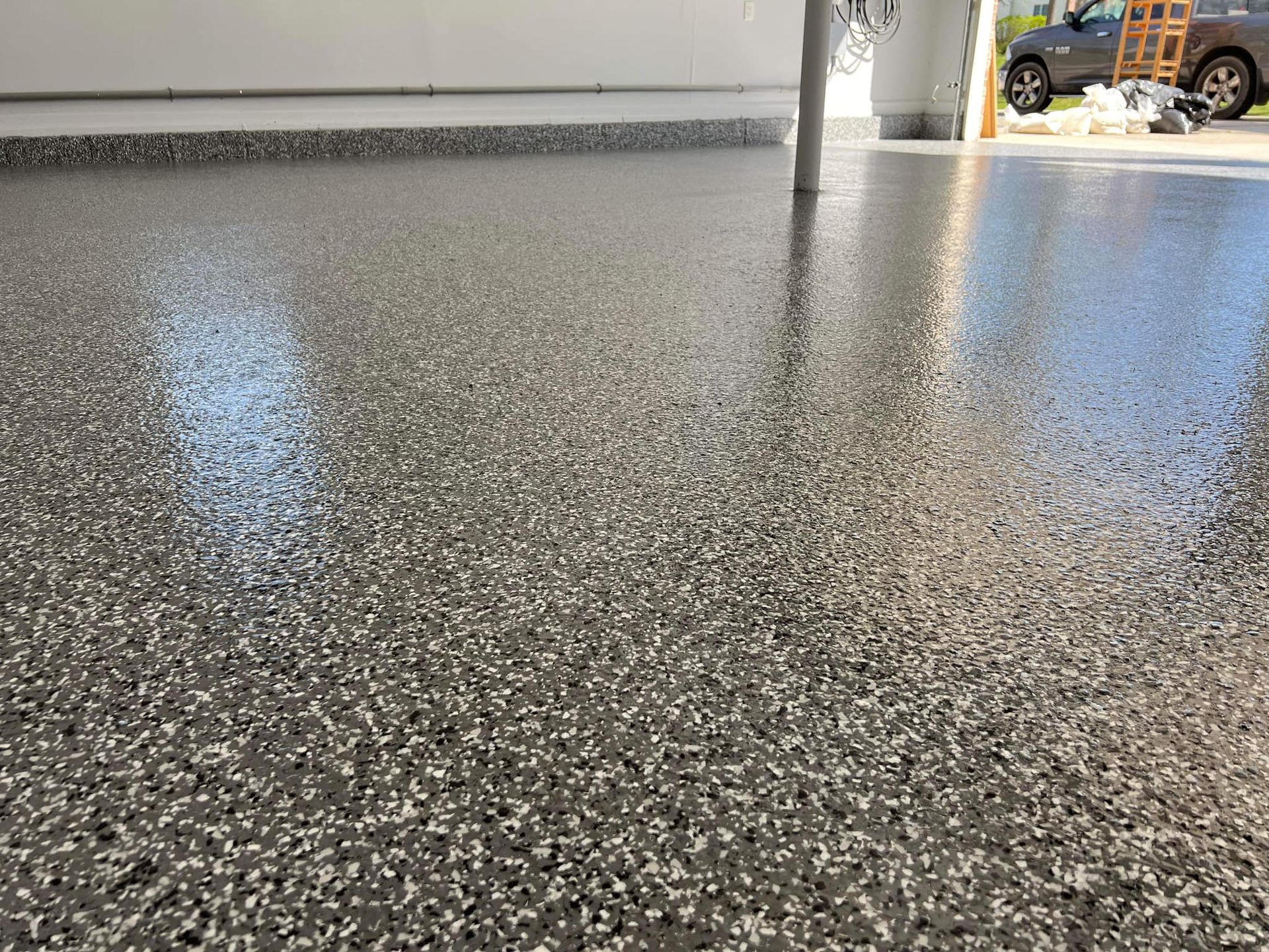 Close-up of a speckled gray epoxy garage floor, reflecting light.