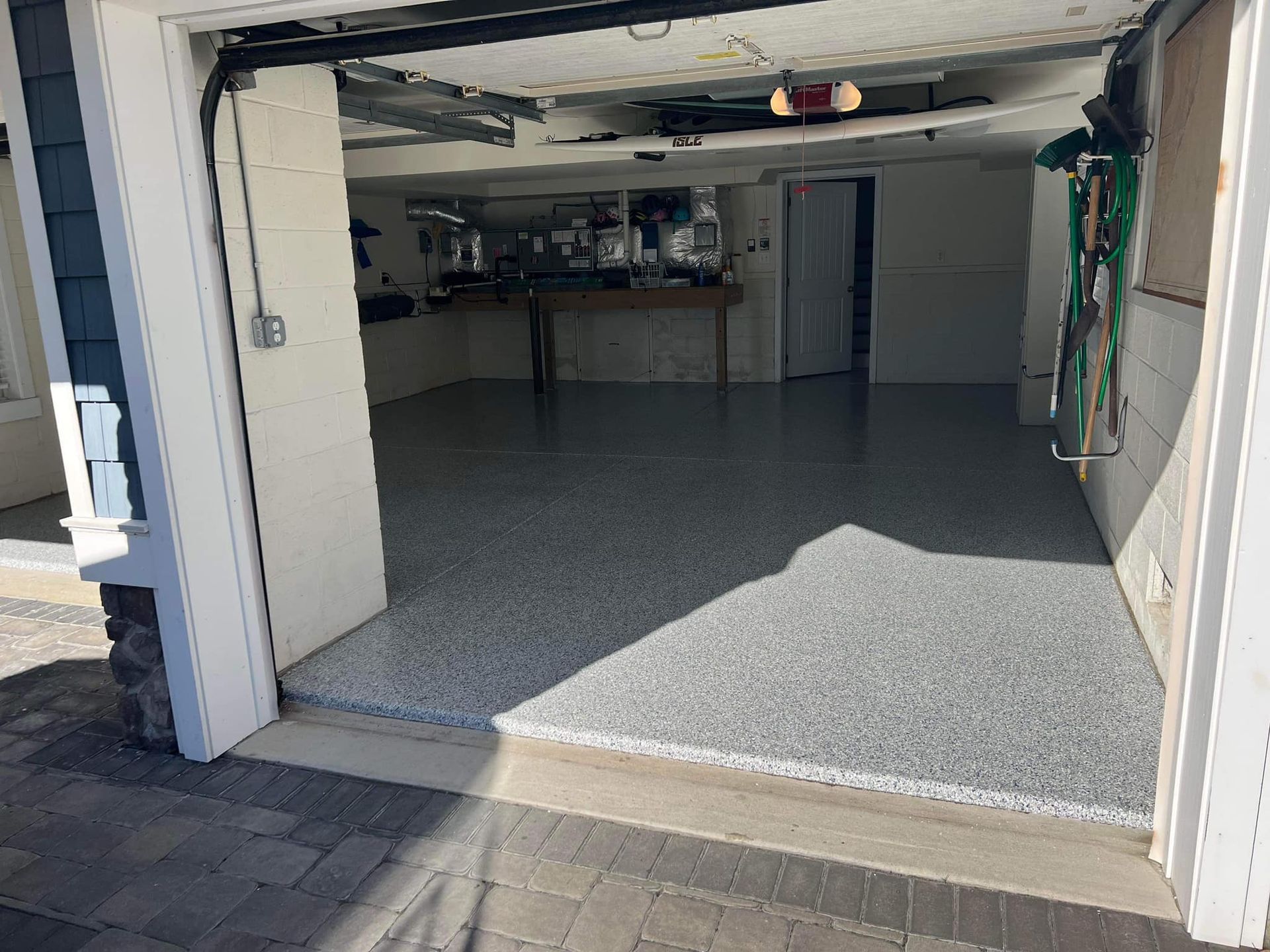 Open garage with gray speckled flooring, light walls, and a workbench in the background.