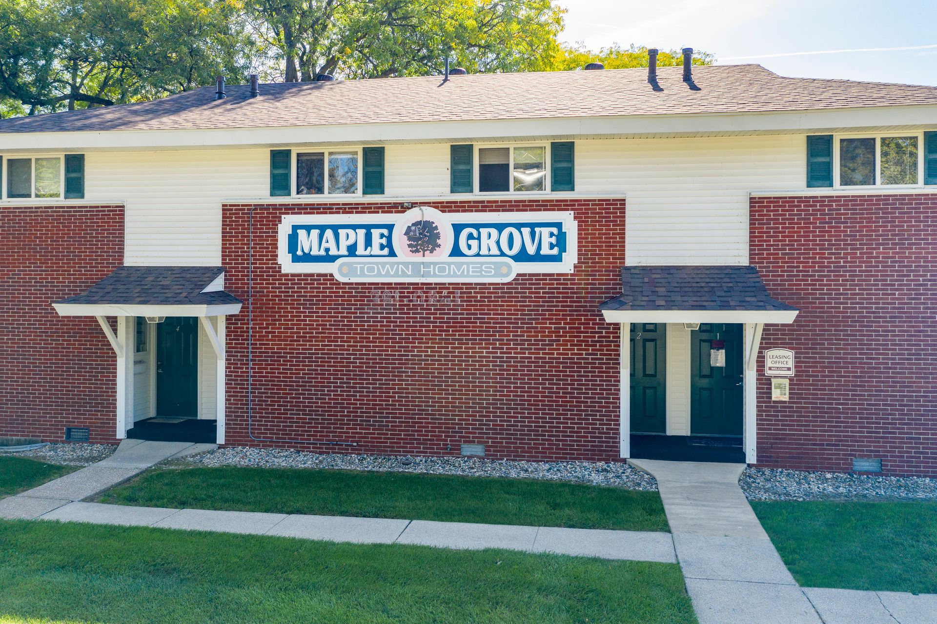 Maple Grove Townhomes, two-story building with red and tan facade, green doors and trim.