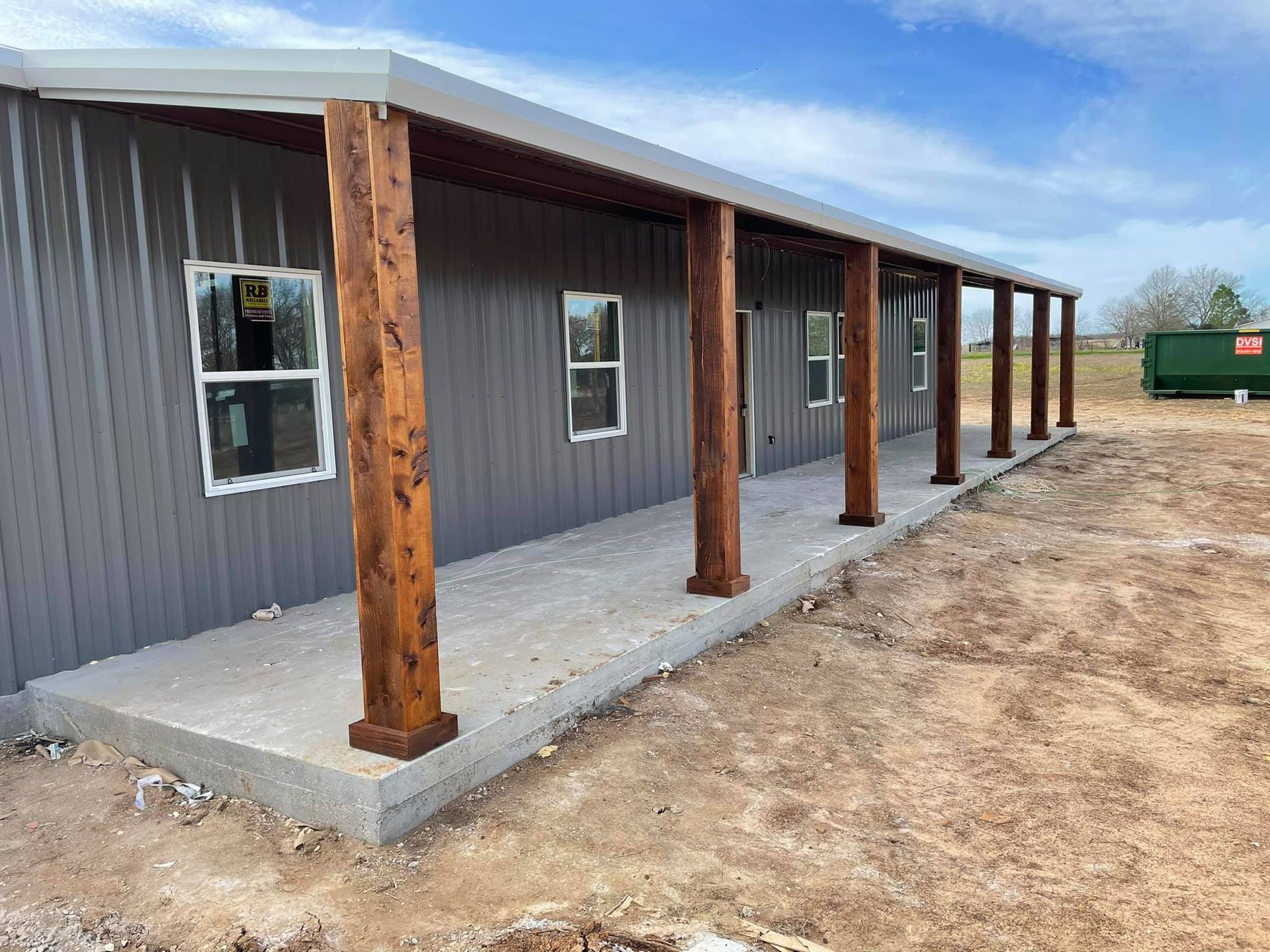 A large metal building with a porch and wooden posts.
