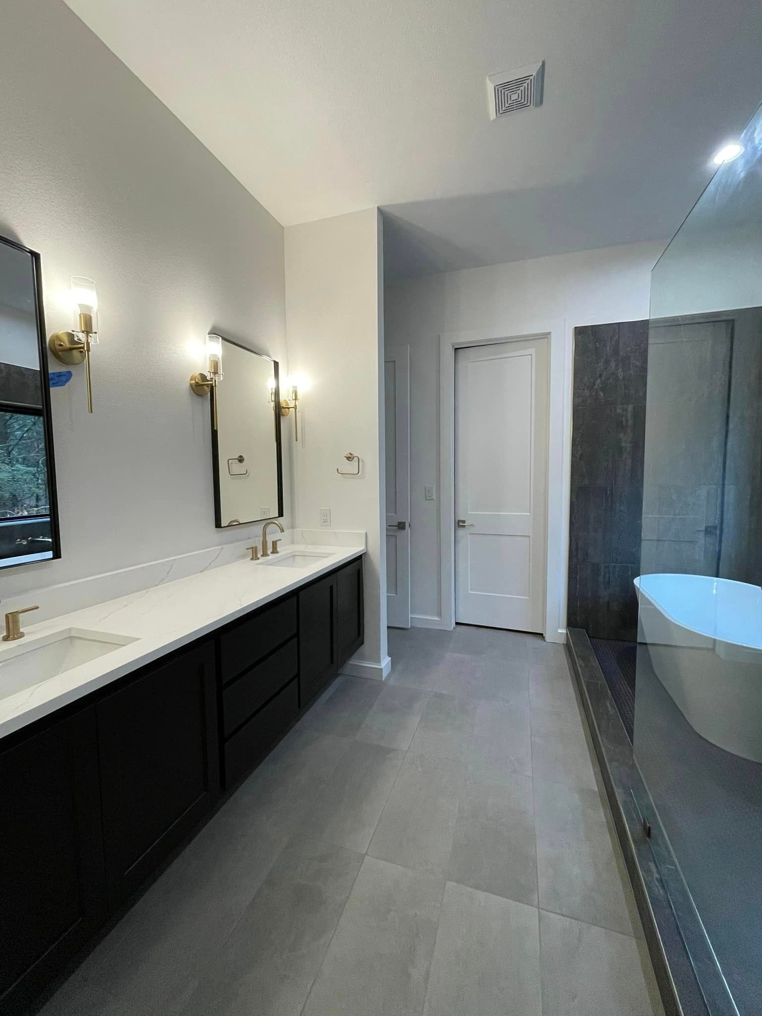 A bathroom with two sinks , two mirrors and a bathtub.