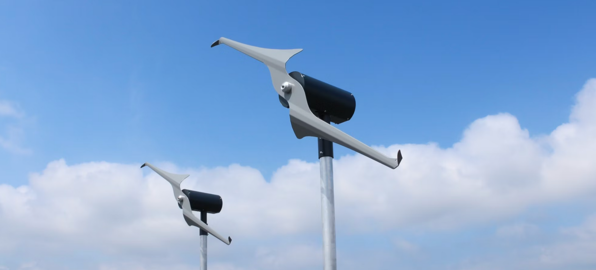 Two wind turbines are against a blue sky with clouds.