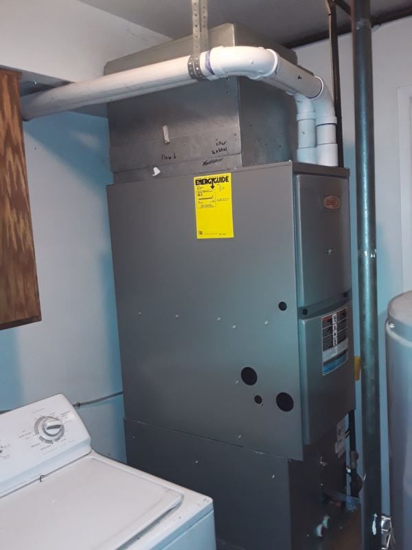 Furnace in a laundry room, with white ductwork, dryer on the left, and water softener on the right.