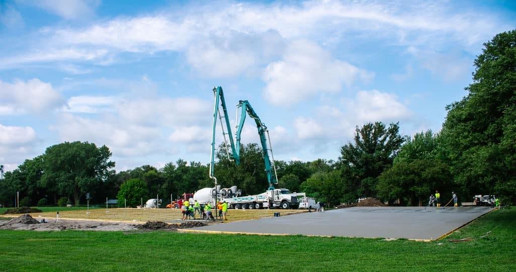 A concrete pump is being used to pour concrete into a field.