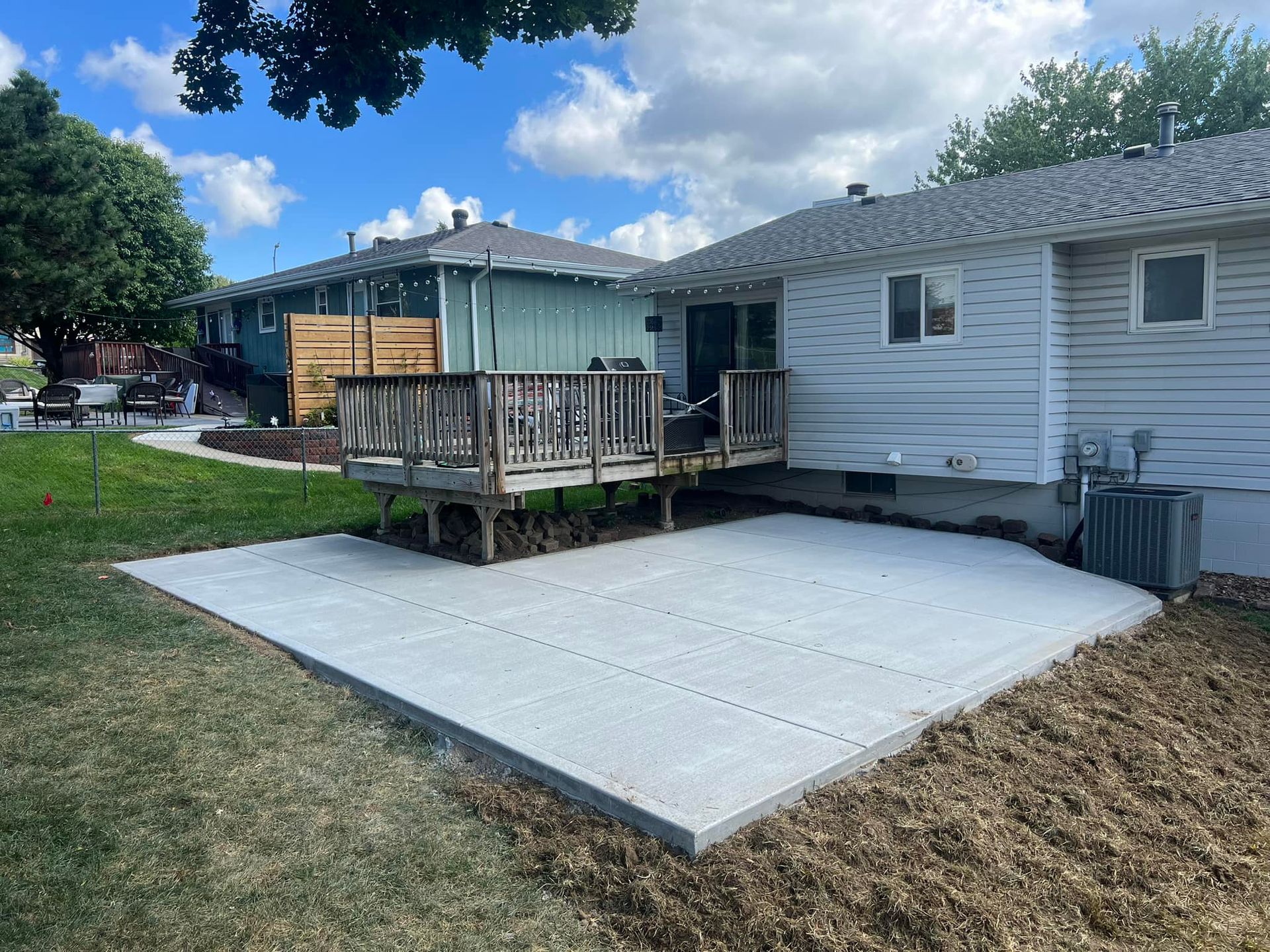 A concrete patio in front of a house with a wooden deck.