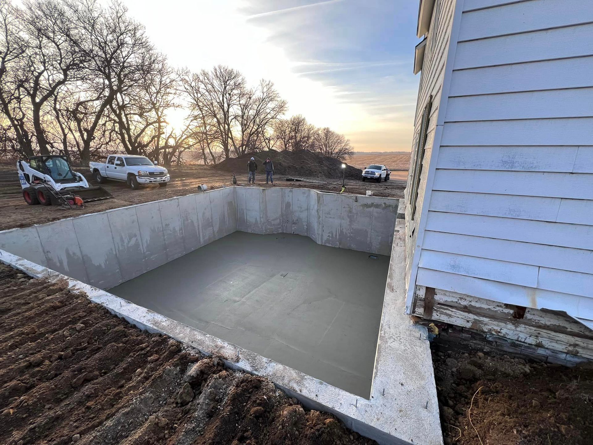 A large concrete pool is being built next to a house.