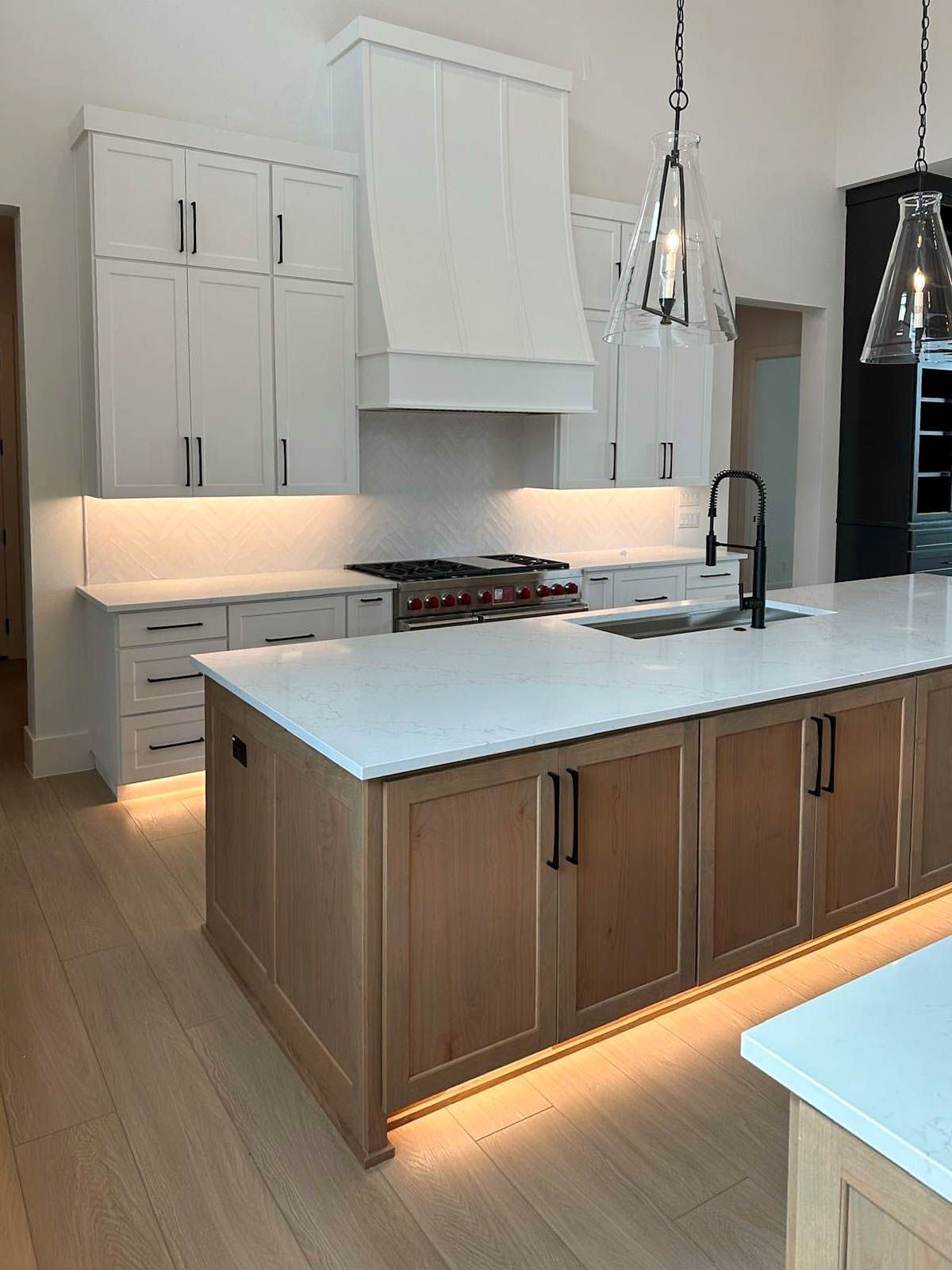 Elegant white and gray kitchen with island, cabinets, and chandelier lighting.