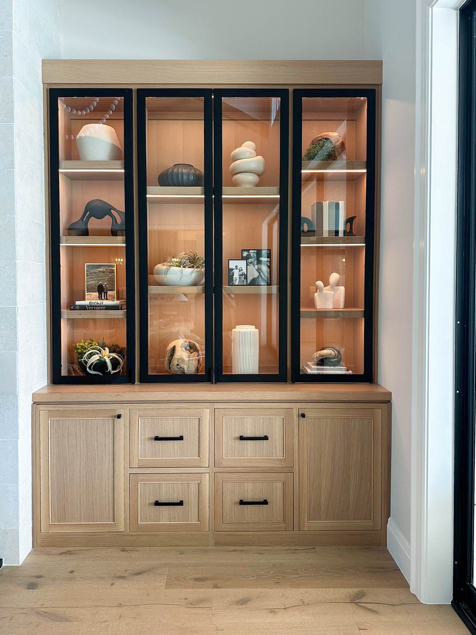 Wooden media center with TV, black shelving, and light-colored marble accents in a living room.