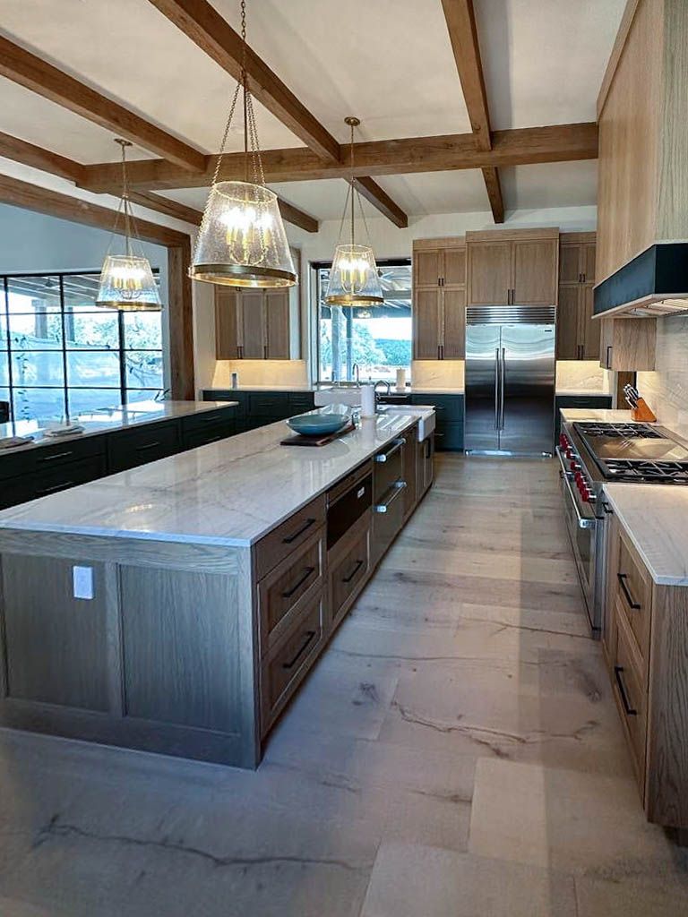 White, modern house with a concrete driveway and landscaping. Olive tree in front, shrubs along the side.