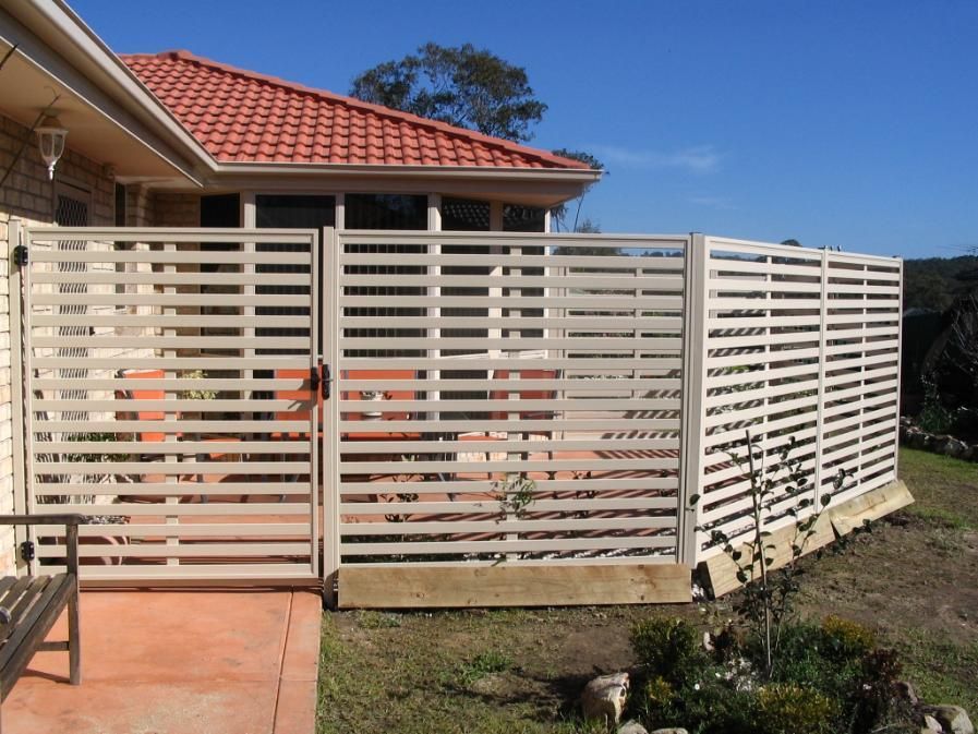 A White Fence Surrounds a House With a Red Tile Roof — Hunter Valley Lattice in Newcastle, NSW