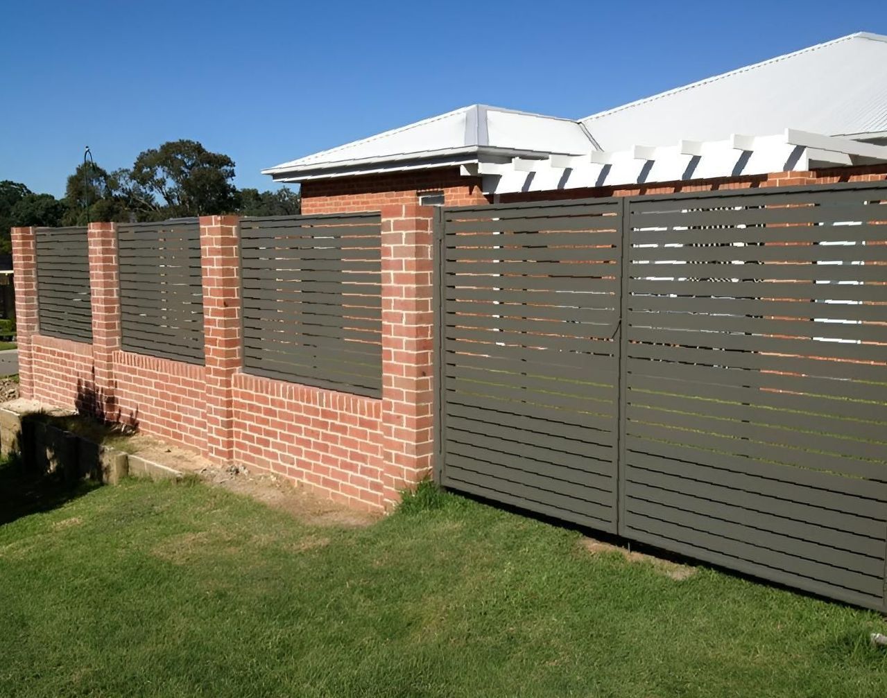 A Brick Wall With a Metal Fence in Front of a House — Hunter Valley Lattice in Newcastle, NSW