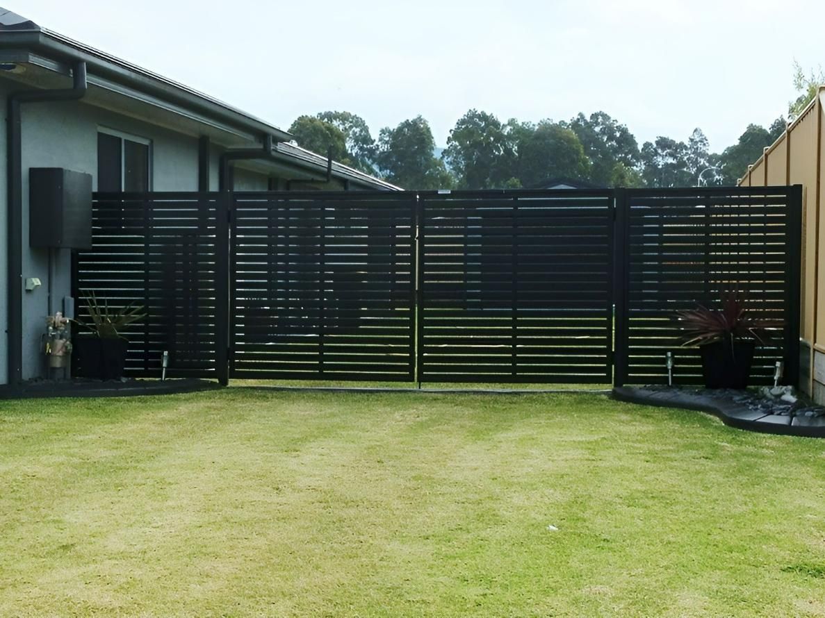 A Black Fence is Surrounding a Lush Green Yard in Front of a House — Hunter Valley Lattice in Lake Macquarie, NSW
