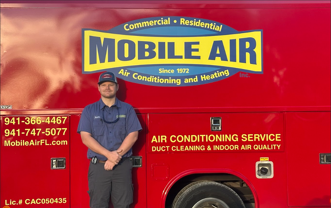 Man standing in front of a red Mobile Air service truck. The truck has the company's logo and contact information.