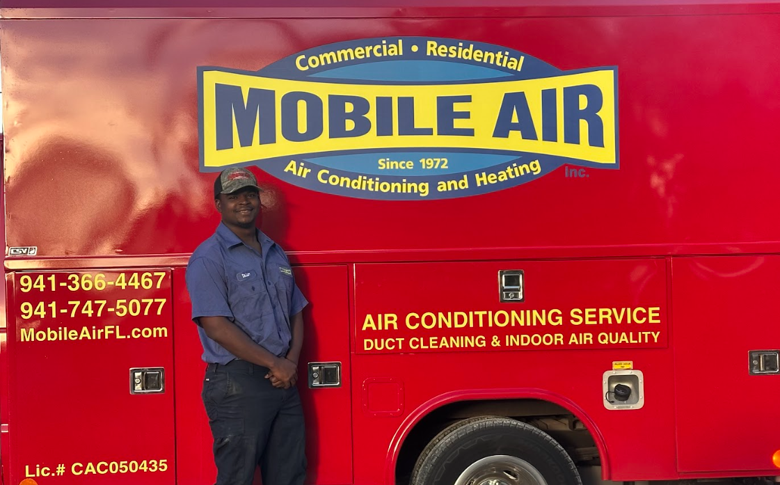 Man in blue uniform stands next to a red Mobile Air truck. Text on the truck includes 