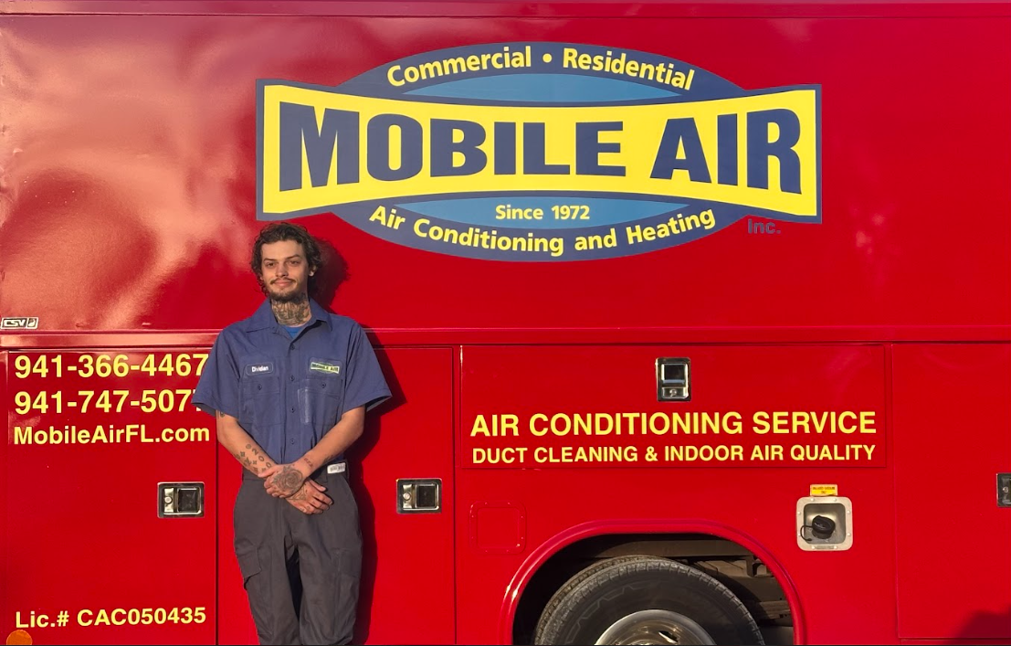 Man in uniform standing in front of a red Mobile Air truck.