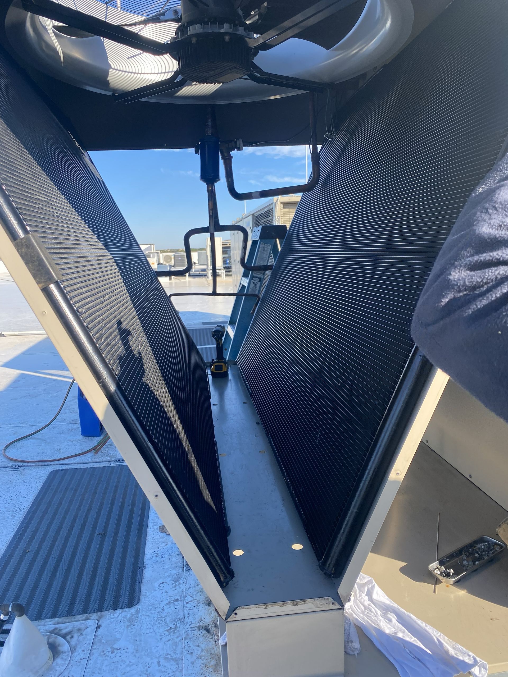 View inside a cooling tower with patterned black fill, a fan, and sky.