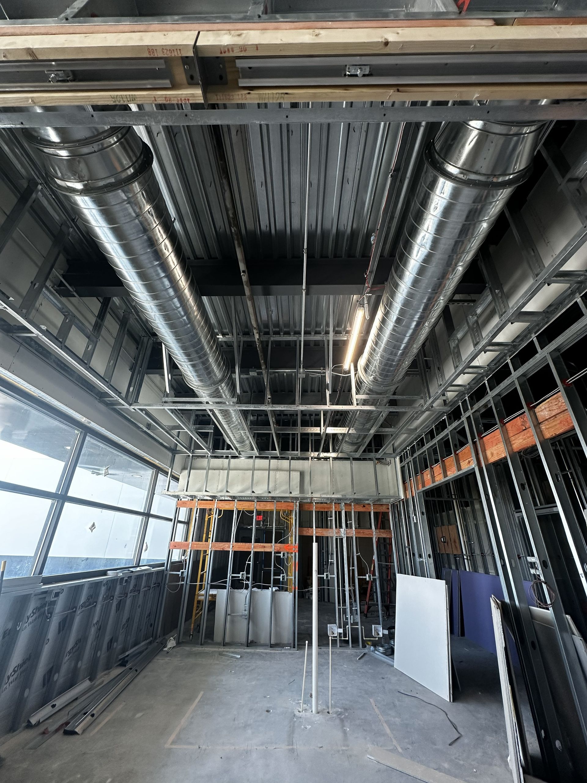 Construction site interior with metal framing, ductwork, and exposed ceiling.