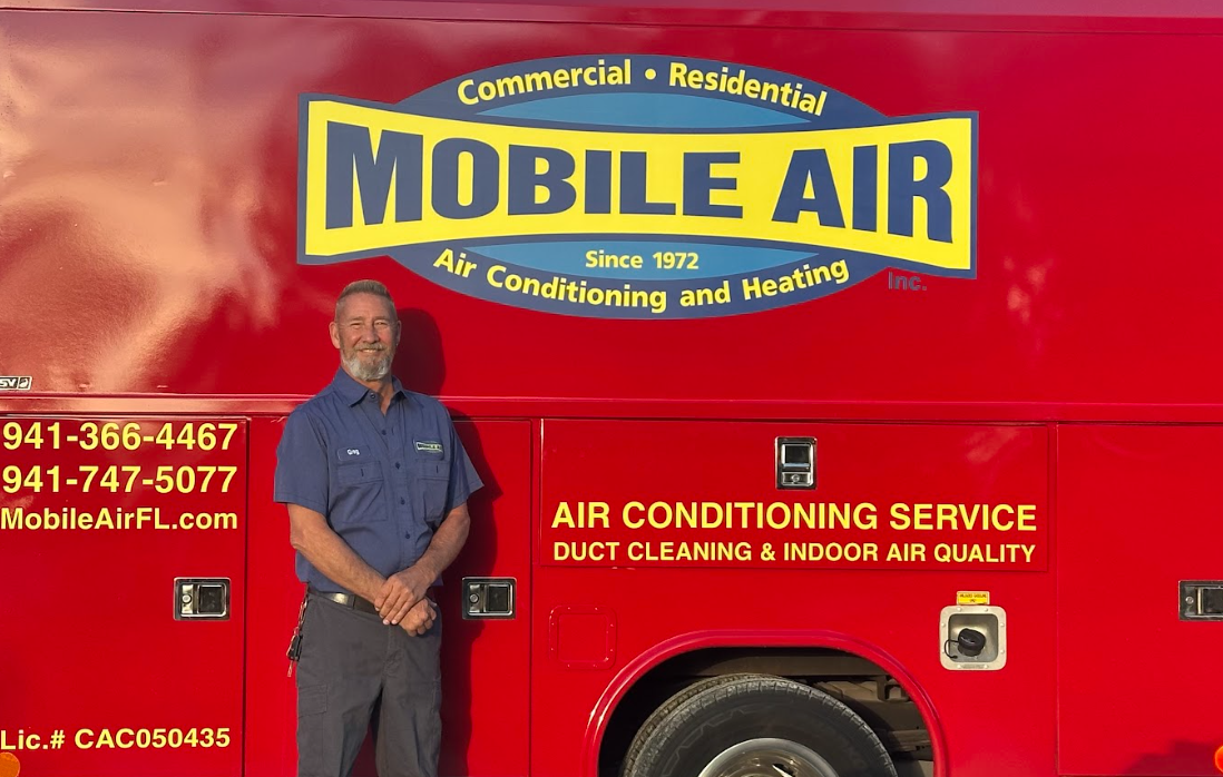 Man stands beside a red Mobile Air service truck, advertising air conditioning and heating services.