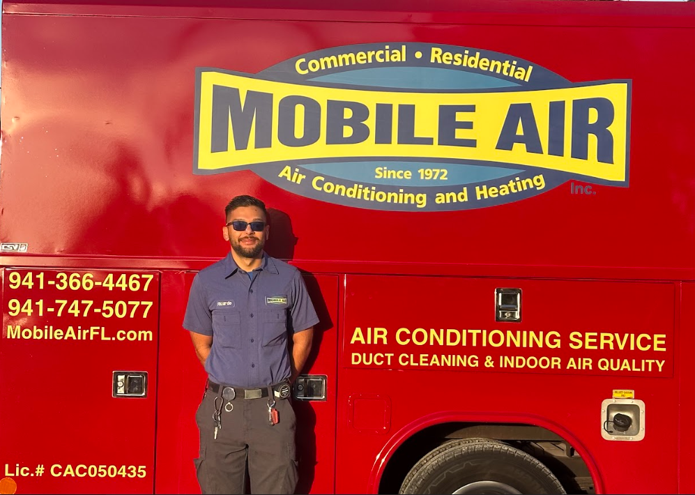 Man in uniform stands in front of a red Mobile Air truck with contact info.