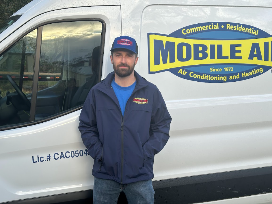 Man in Mobile Air uniform stands in front of a company van.