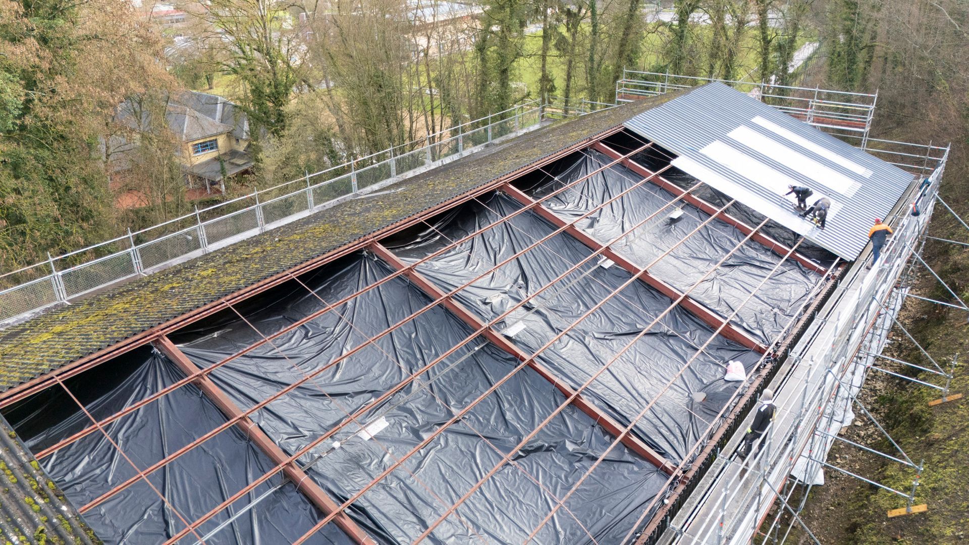 Nettoyage d'un toit de tuiles rouges au nettoyeur haute pression ; de la mousse verte est visible.