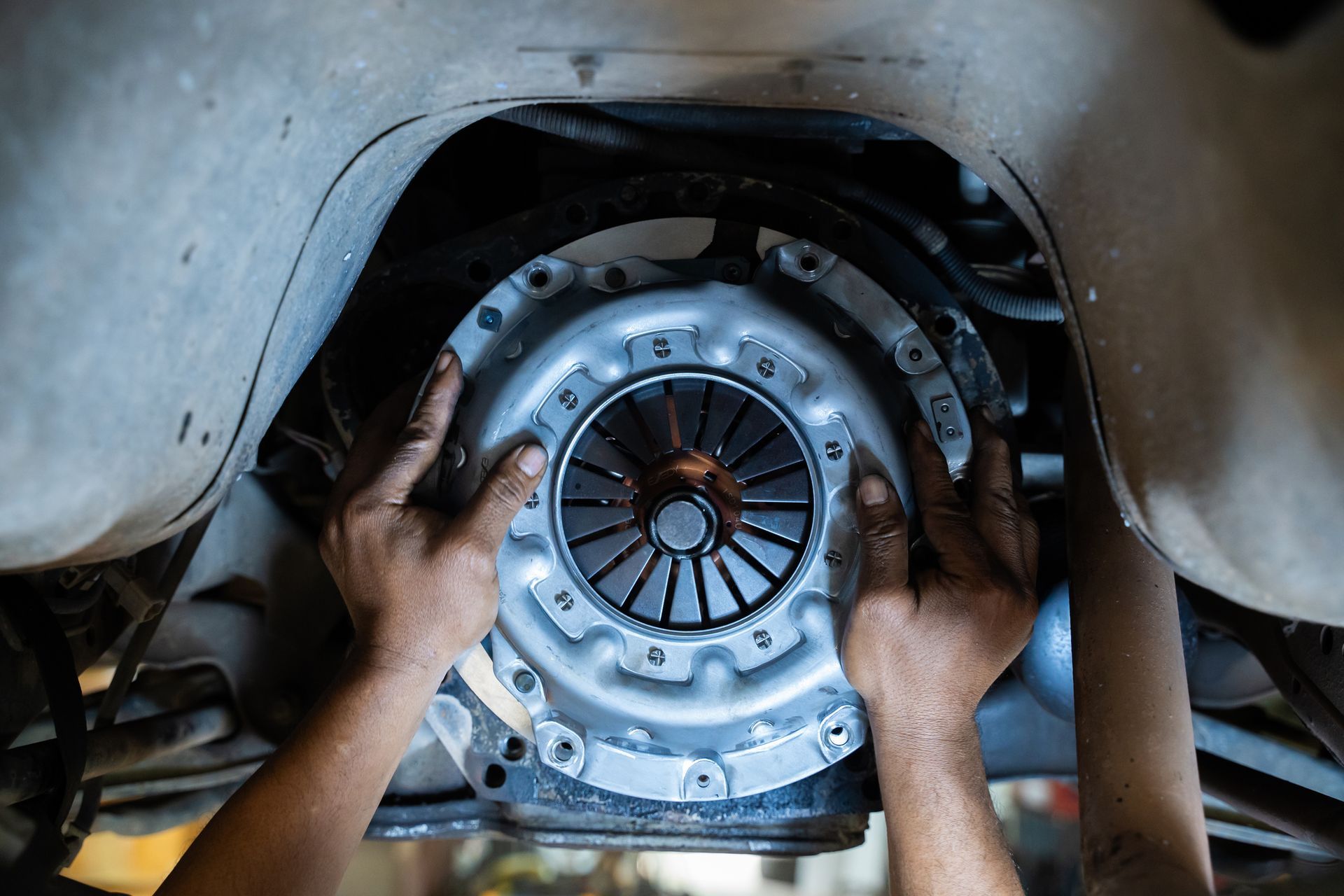Mechanic servicing the clutch system inside a busy auto repair garage