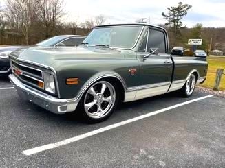 Green and white vintage GMC pickup truck parked on asphalt. Chrome wheels and trim.