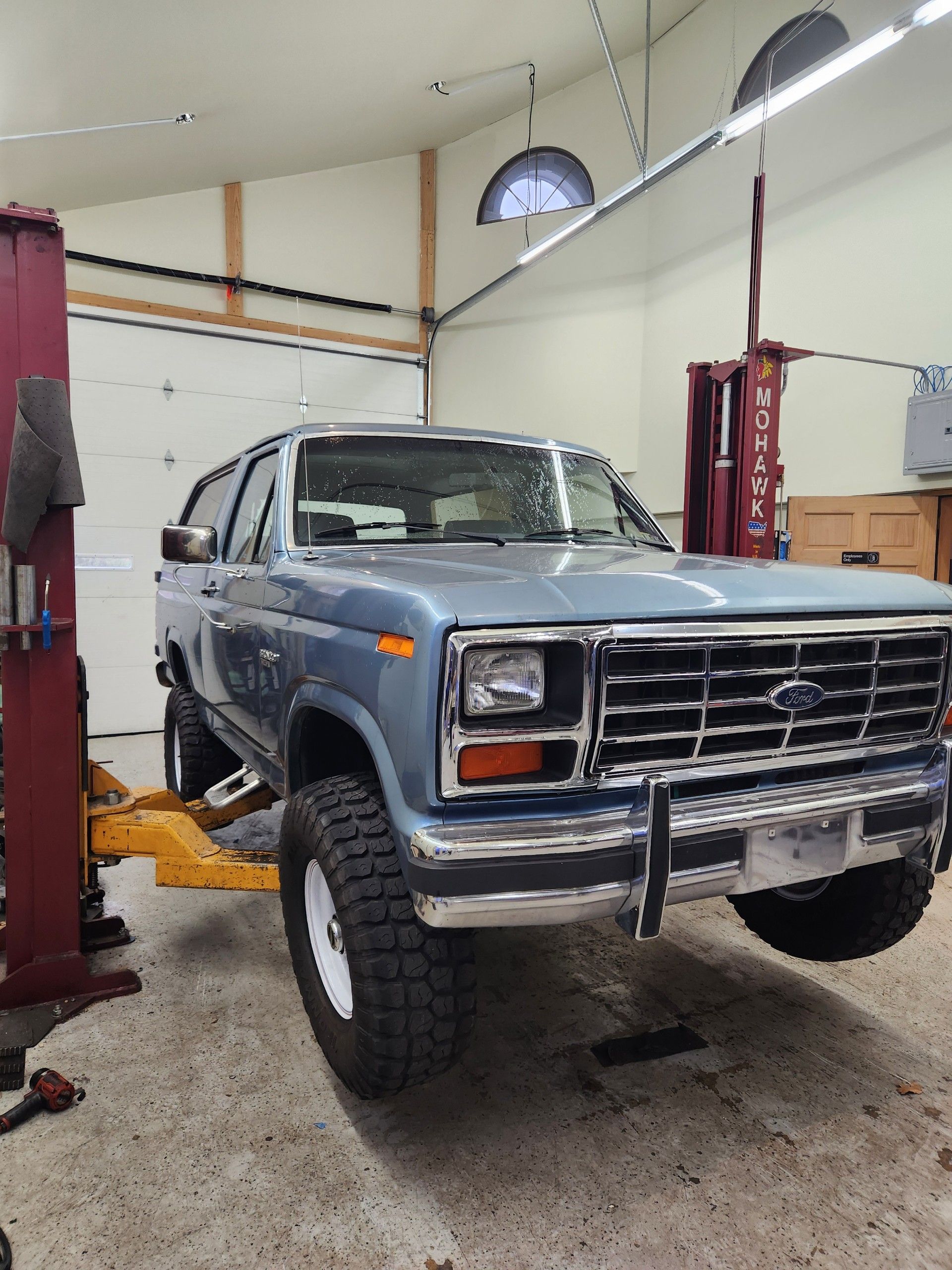 Blue Ford Bronco SUV on a lift in a garage.