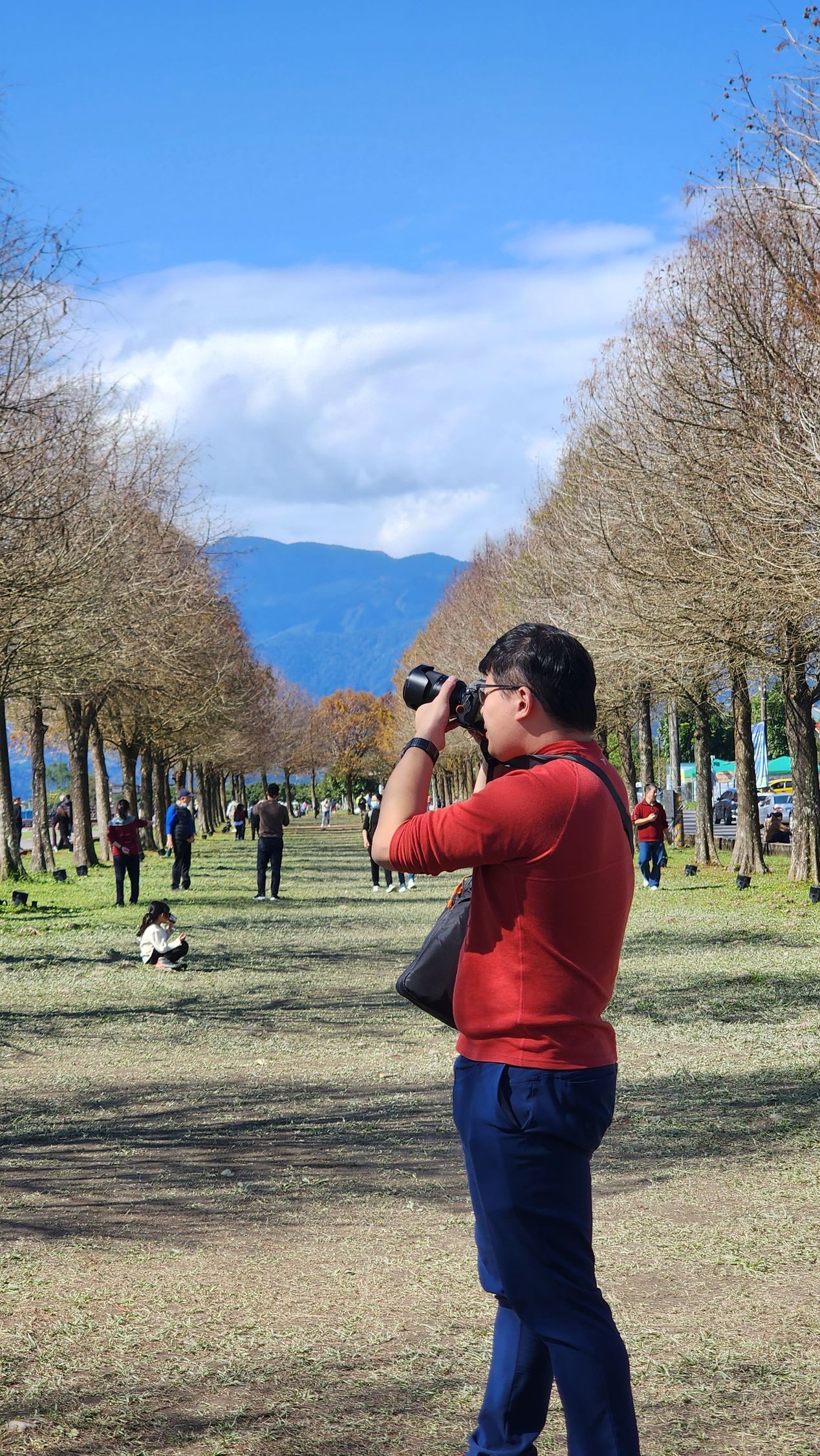 一名戴眼鏡的男子正在調整三腳架上的相機,其他人則站在背景中。