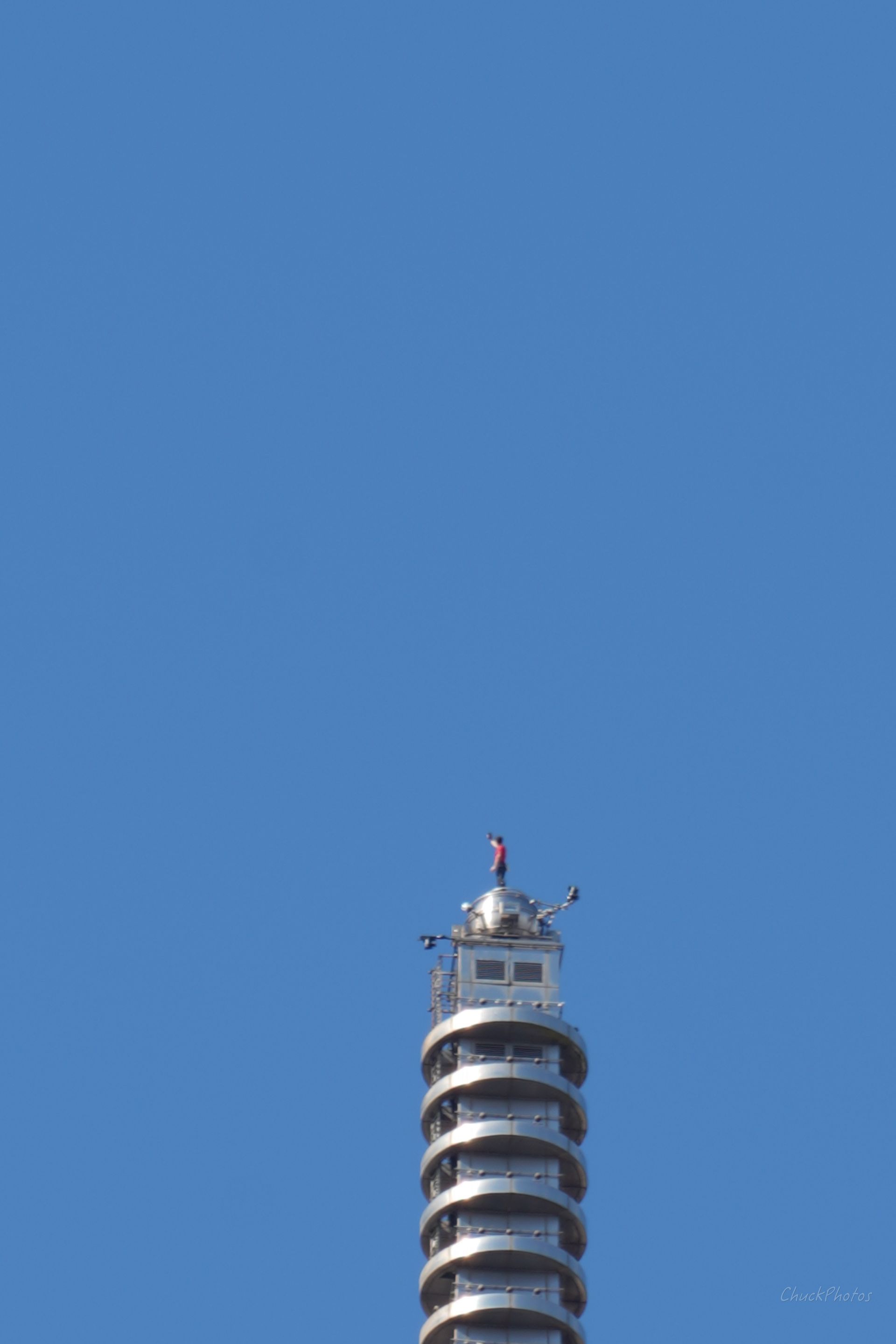 Tall, cylindrical white tower with spiral tiers topped with a small structure; against a clear blue sky.