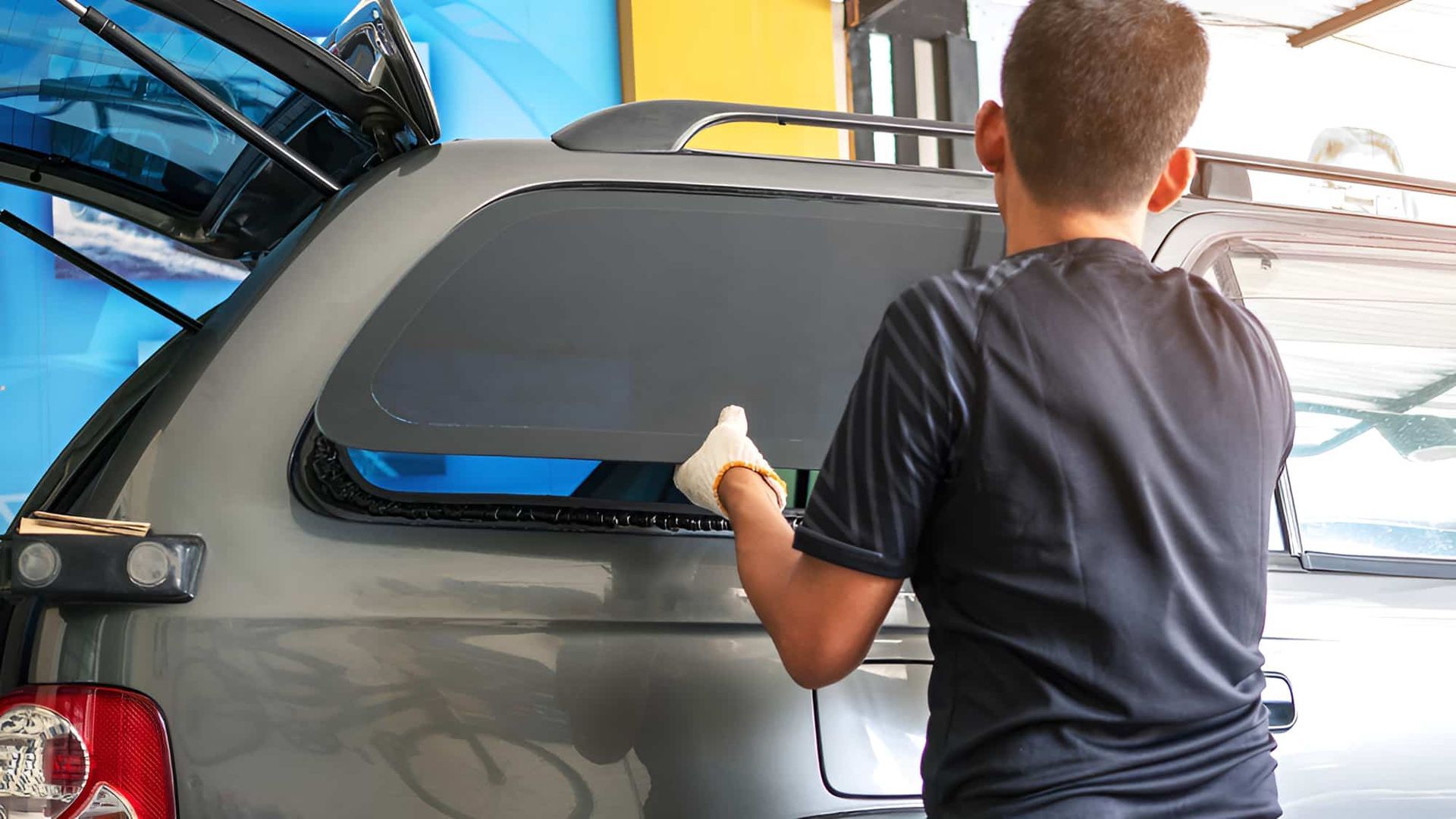 A Man Is Installing A Window Tint On A Car — Raymond Terrace Windscreen Services In Raymond Terrace, NSW