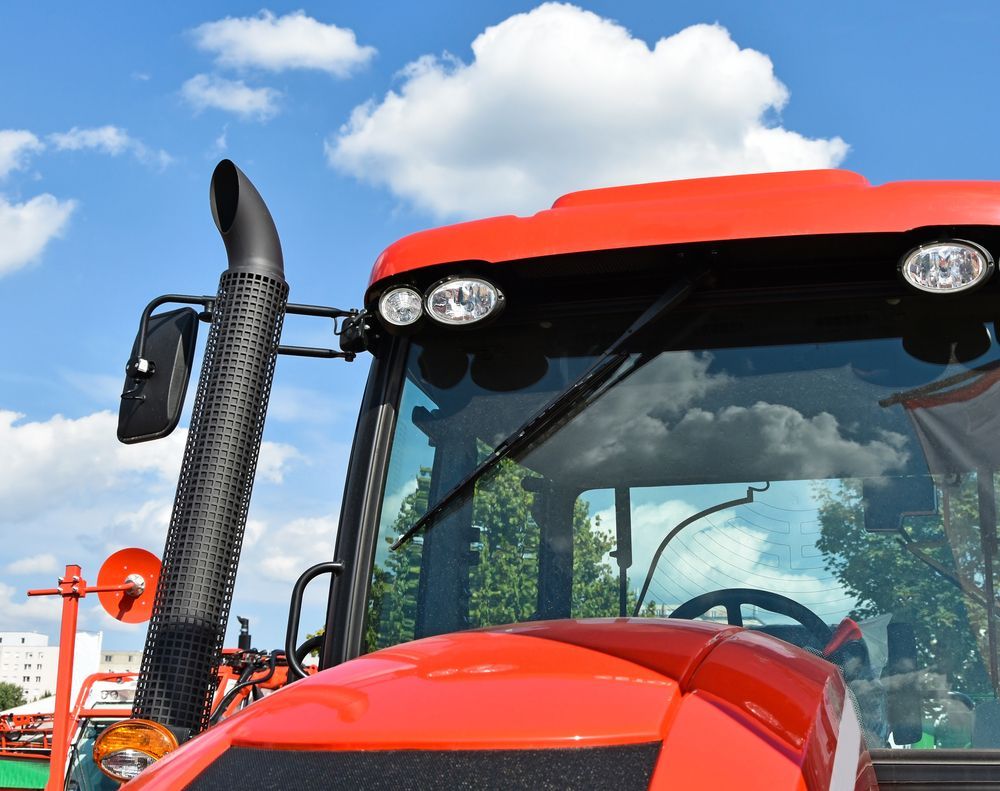 A Red Tractor Is Parked In Front Of A Blue Sky — Raymond Terrace Windscreen Services In Lake Macquarie, NSW