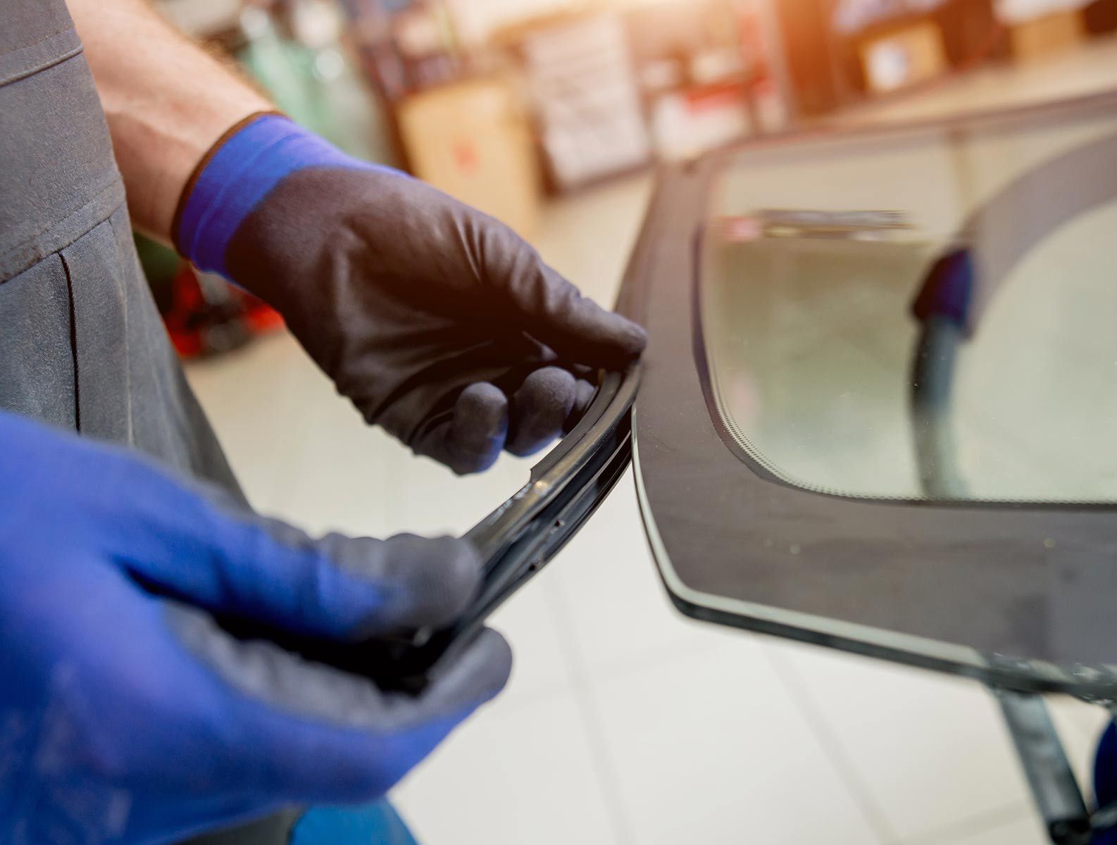 A Man Is Installing A Windshield On A Car — Raymond Terrace Windscreen Services In Maitland, NSW