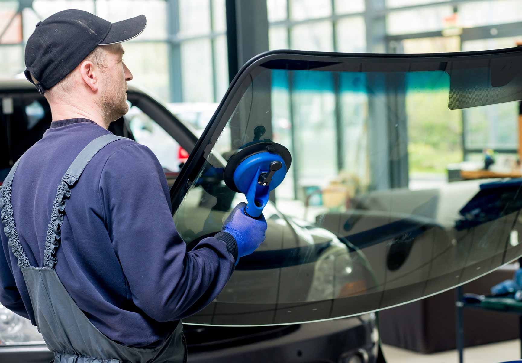 A Man Is Installing A Windshield On A Car — Raymond Terrace Windscreen Services In Raymond Terrace, NSW