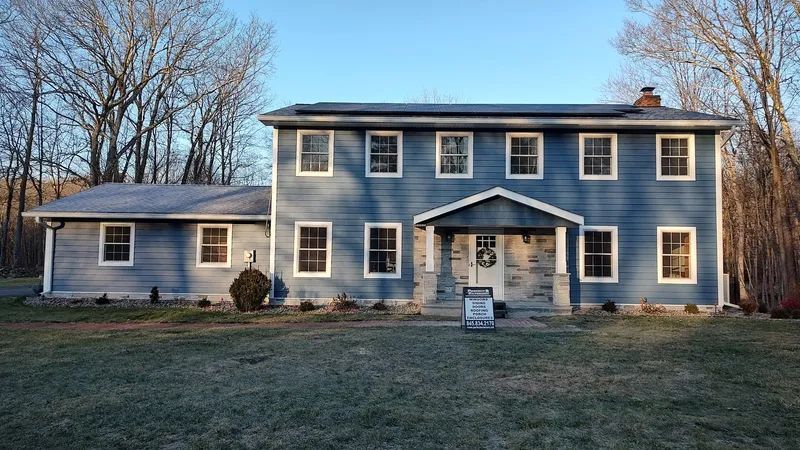 A large blue house with a sign in front of it that says for sale