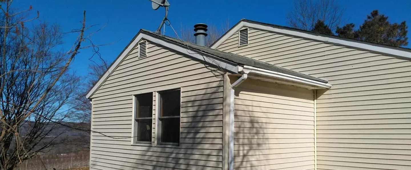 A white house with a chimney on the roof and a blue sky in the background.
