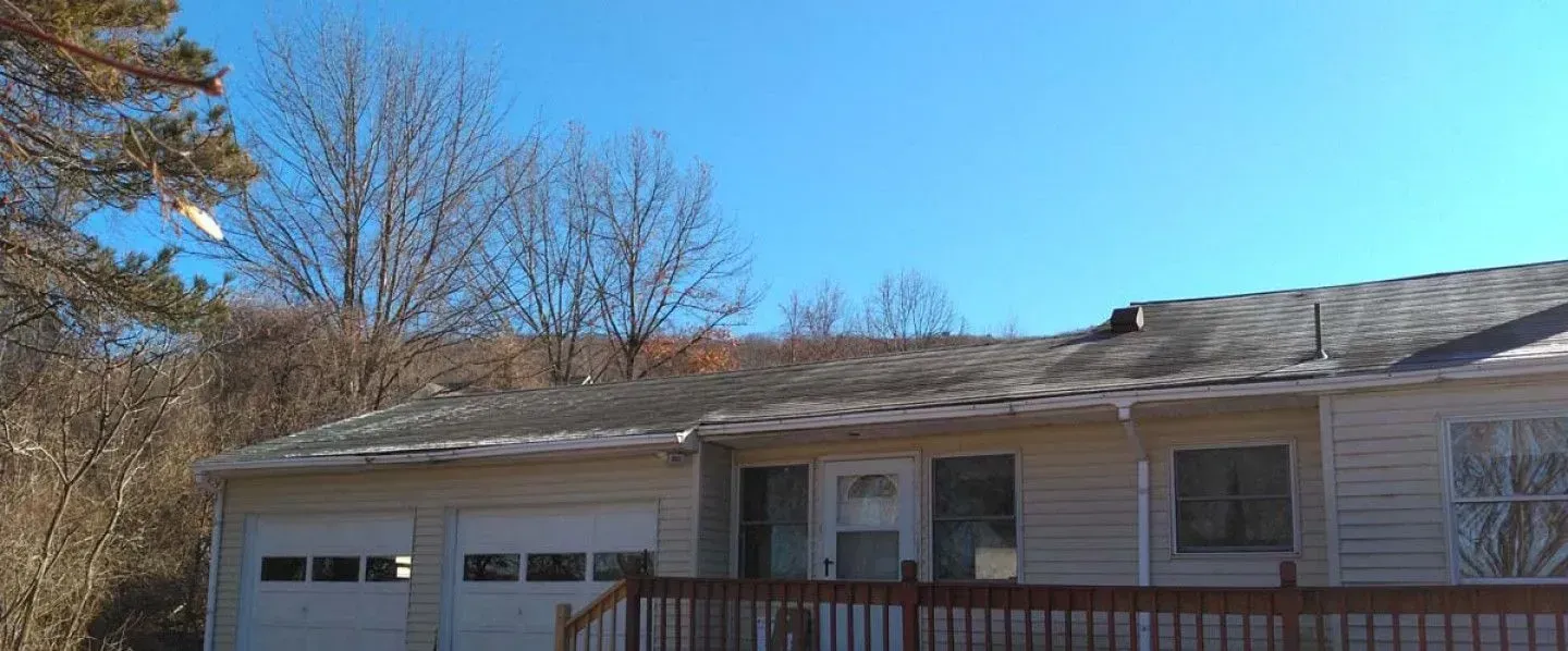 A house with a garage and a deck on a sunny day.